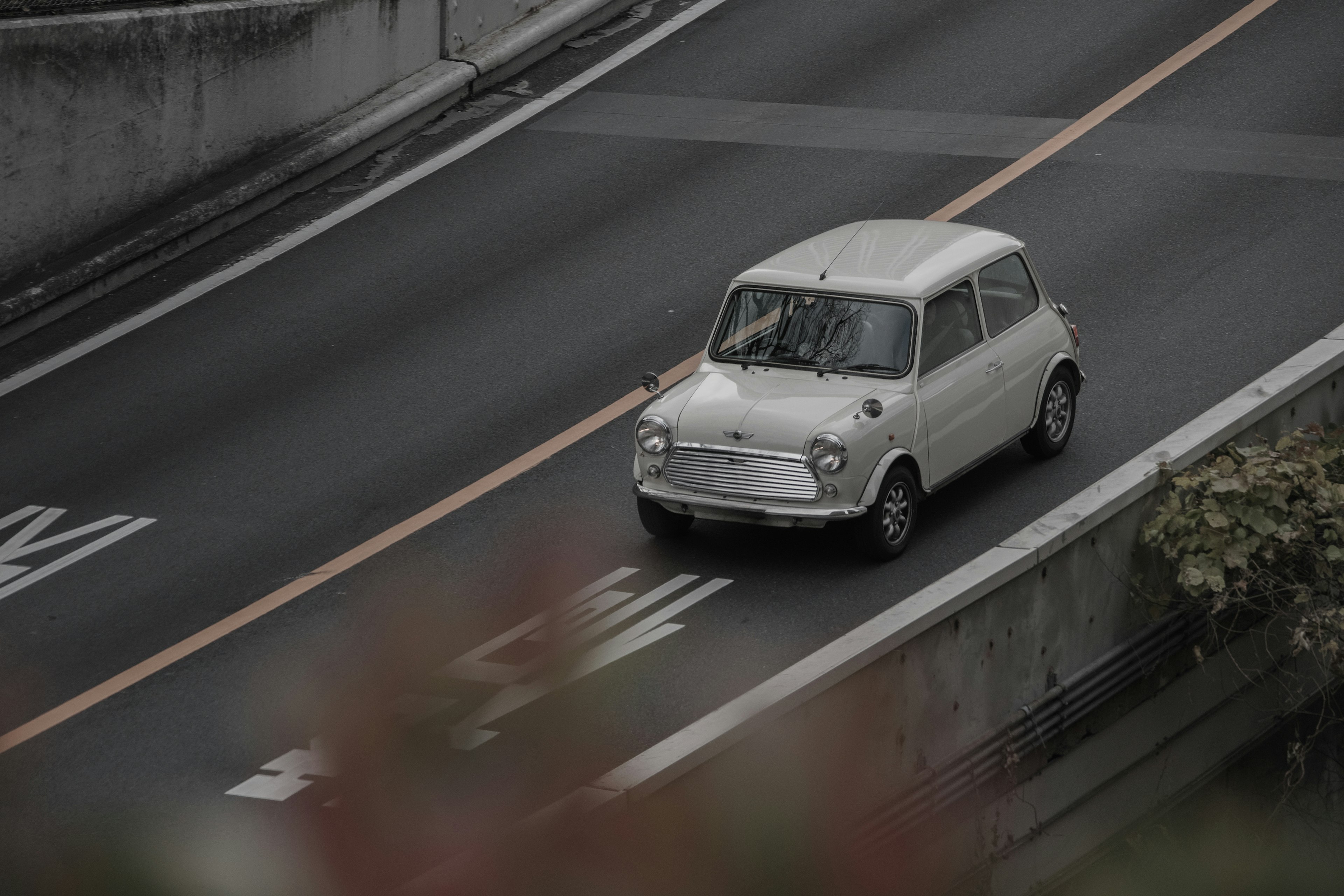 A classic white car driving on a road