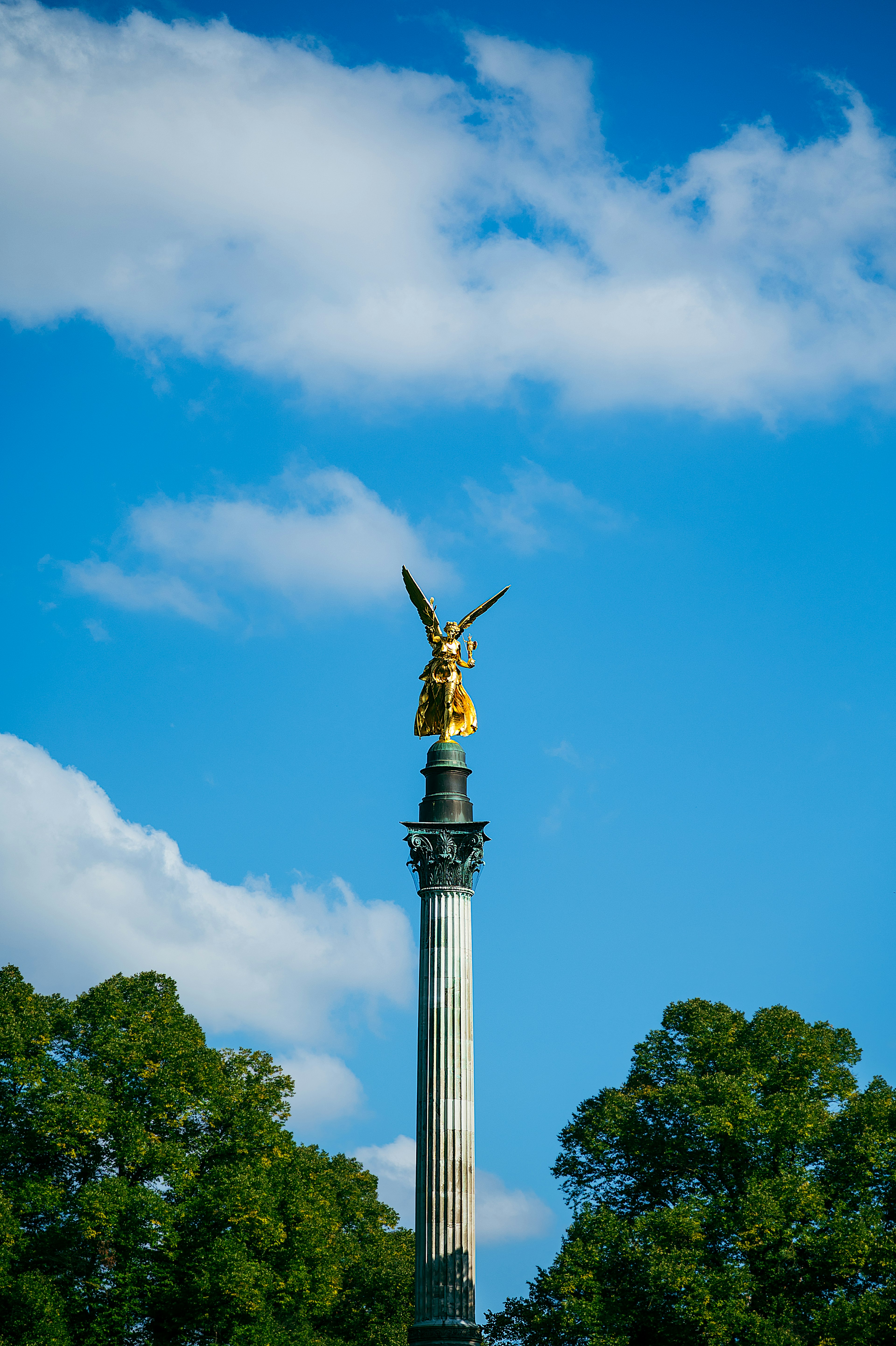 Goldene Statue auf einer hohen Säule unter einem blauen Himmel