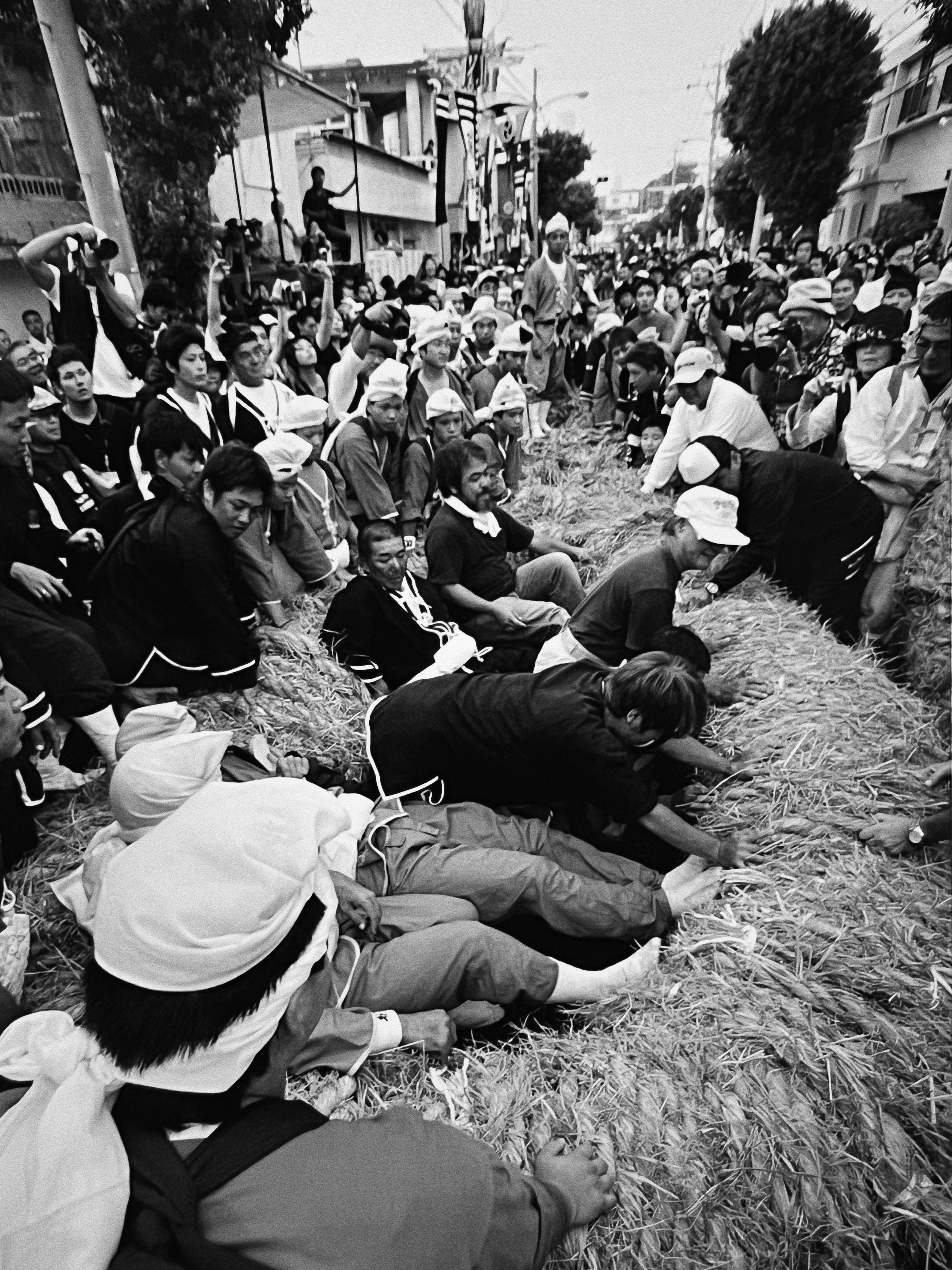 Black and white scene of people lying on straw during a festival