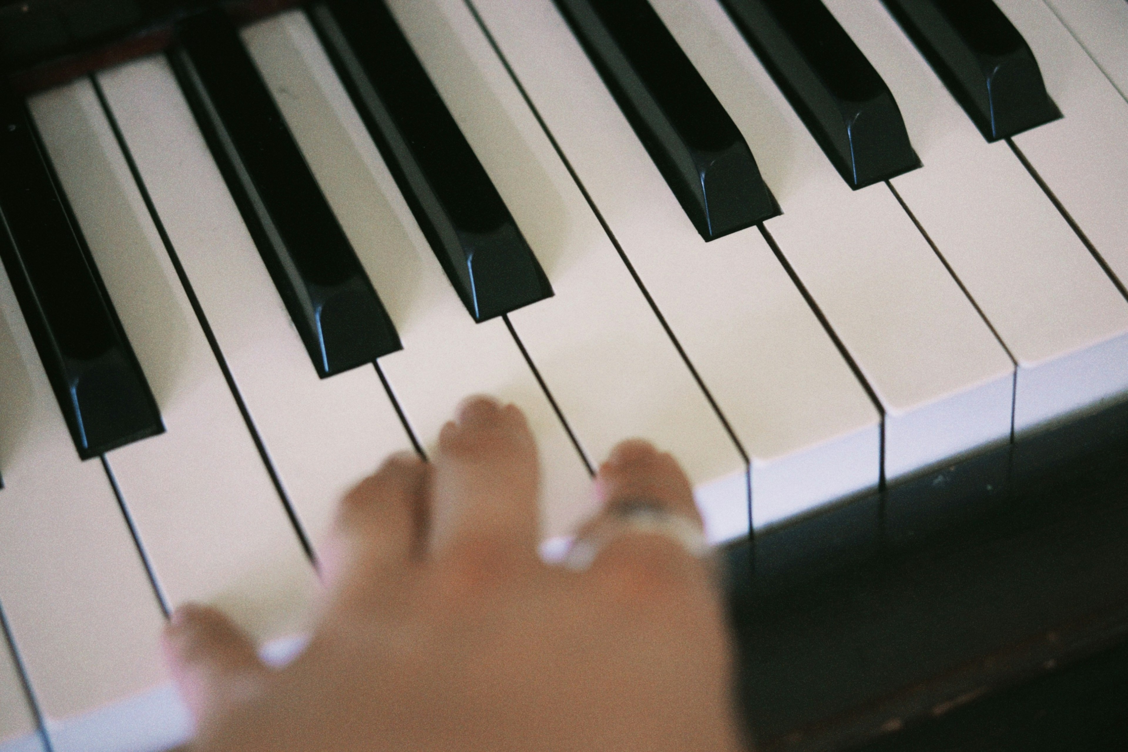 Primo piano di una mano che tocca i tasti di un pianoforte