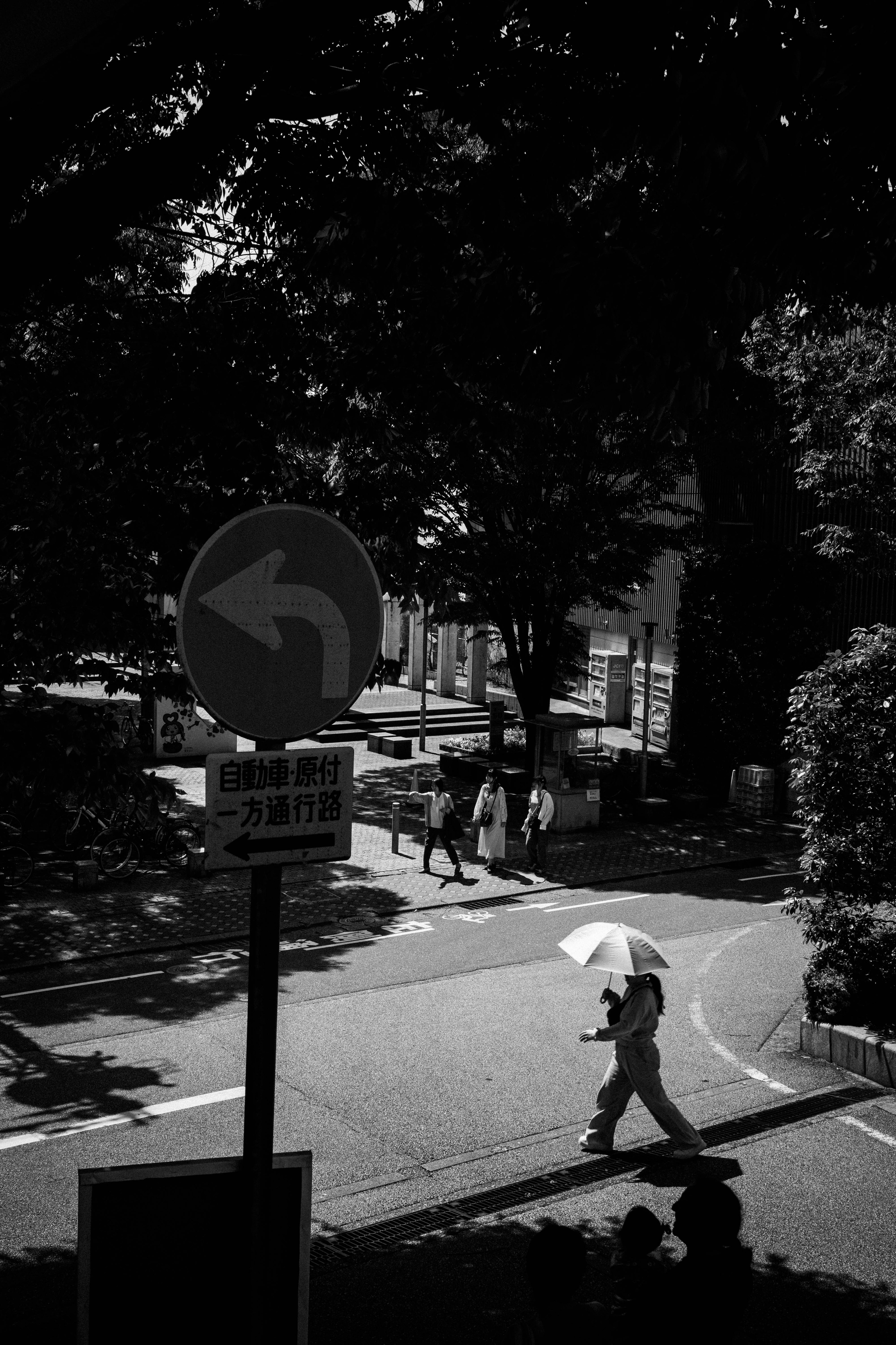 Une personne marchant avec un parapluie noir à un coin de rue