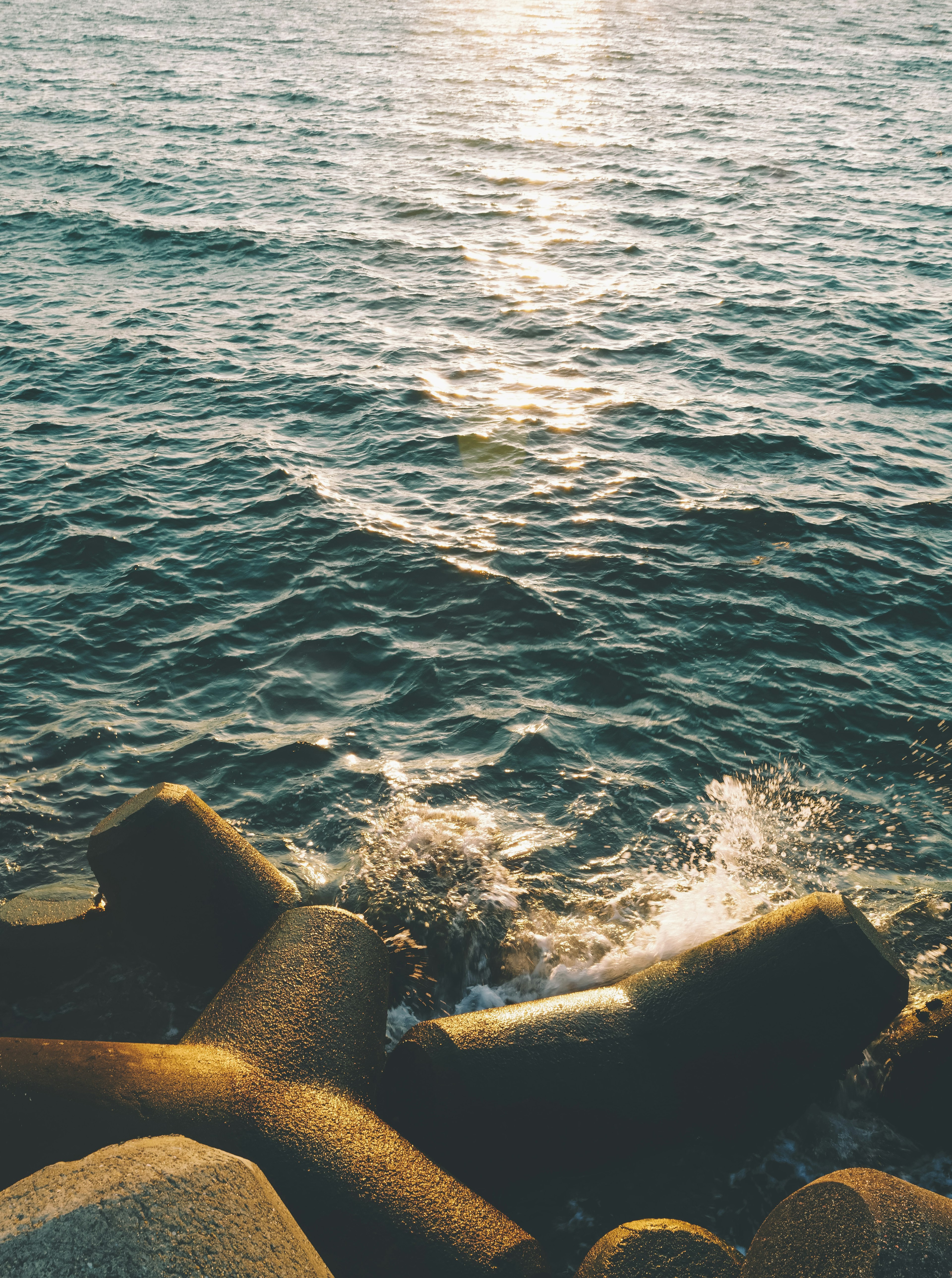 Seascape featuring light reflecting on water and rocky blocks