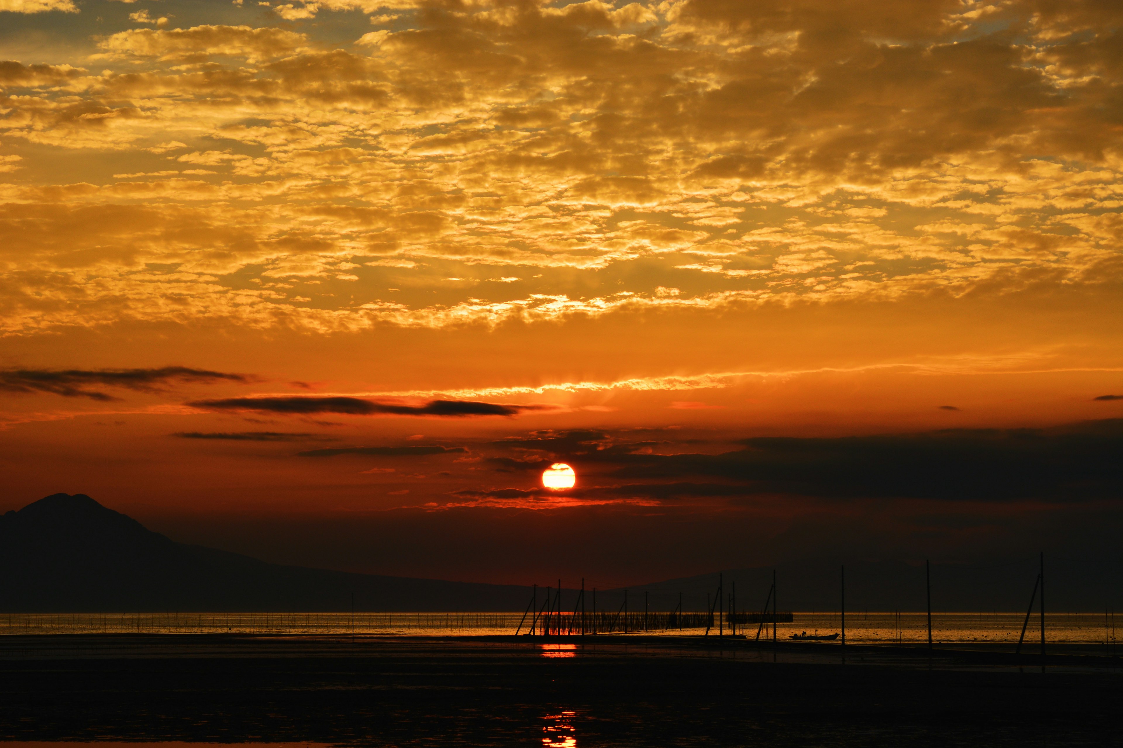 Sunset over the ocean with vibrant orange and red sky sun setting on the horizon