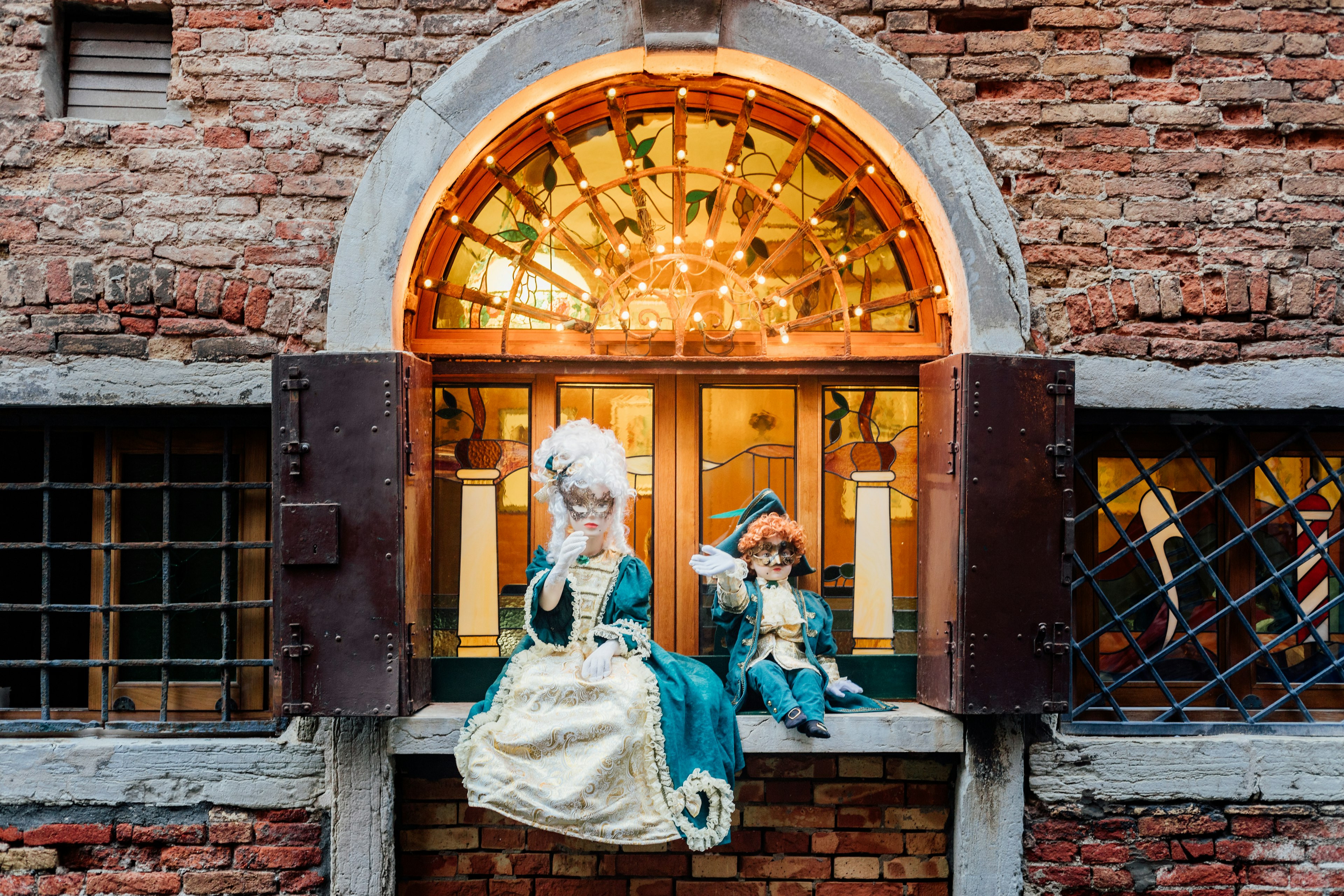 Dos figuras en traje sentadas junto a una ventana en una pared de ladrillo