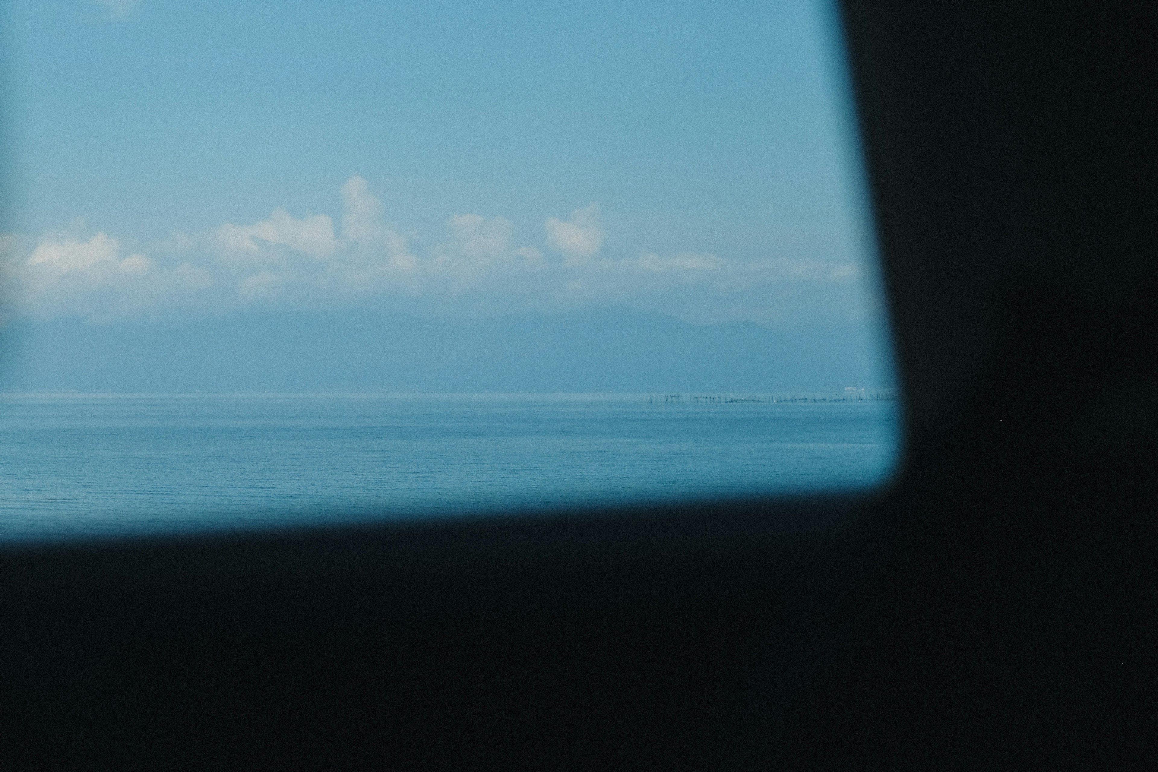 Blick auf das blaue Meer und Wolken durch ein Fenster