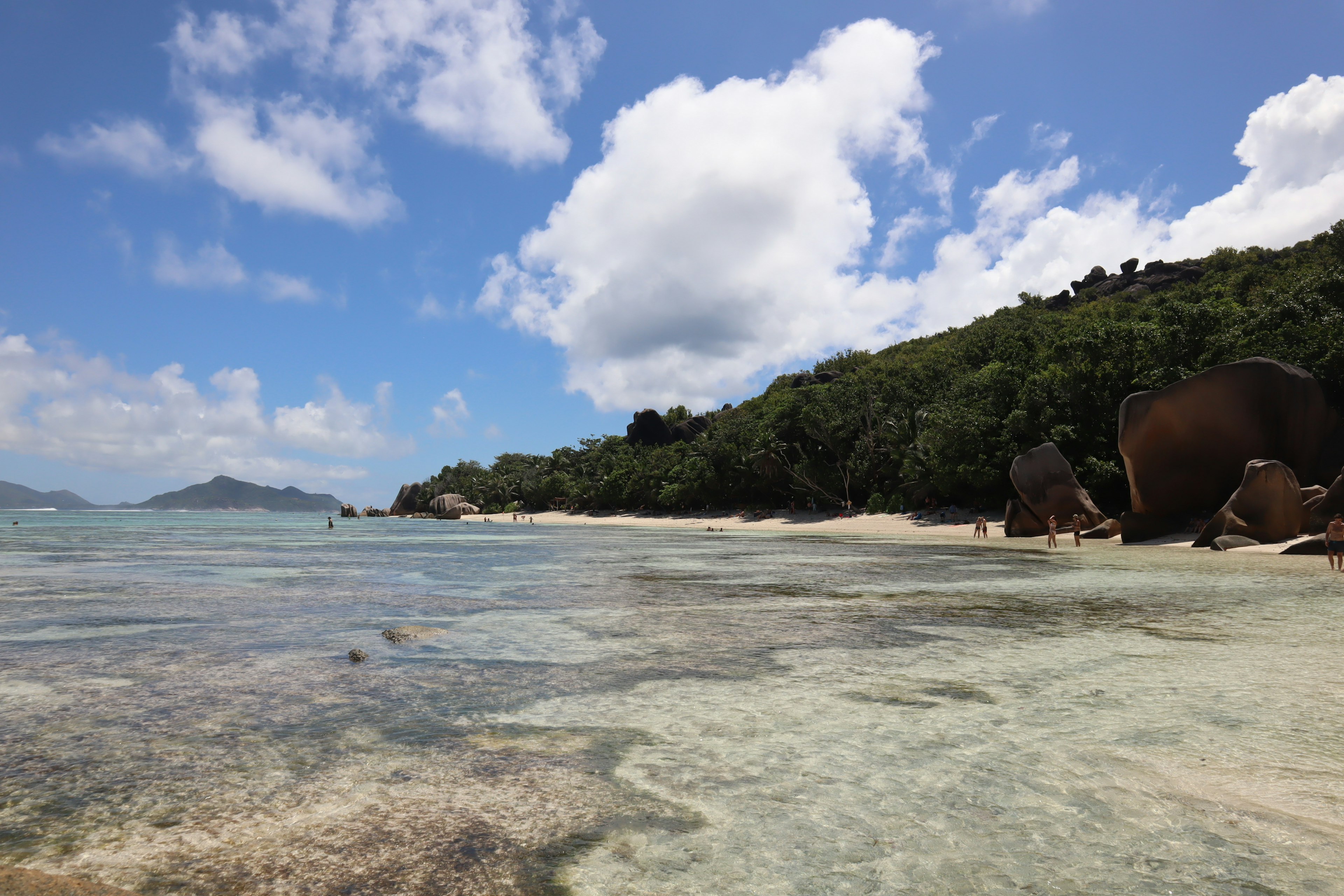 Scenic beach view with clear water blue sky and lush green hills