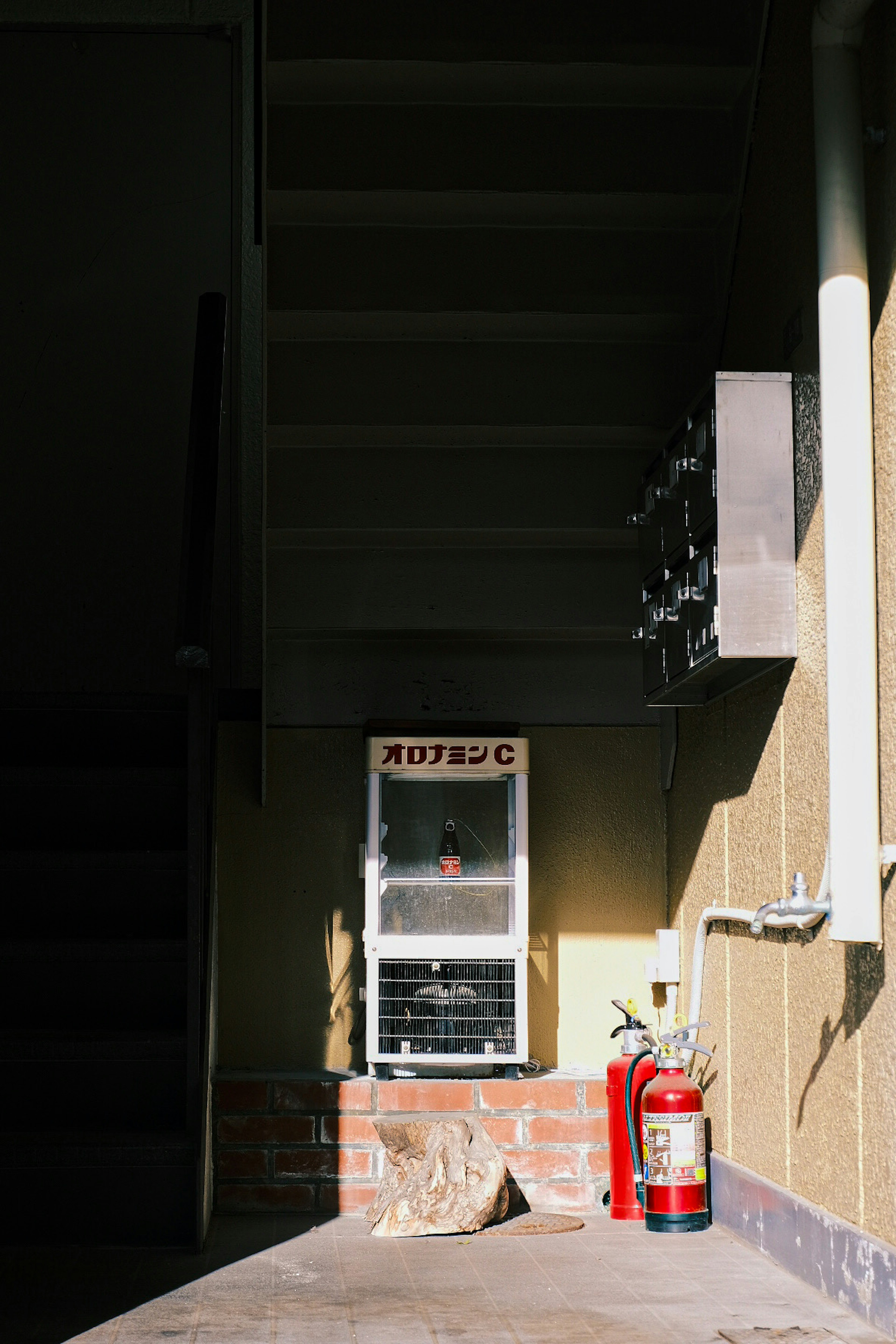 Image of an old vending machine and a fire extinguisher near a staircase