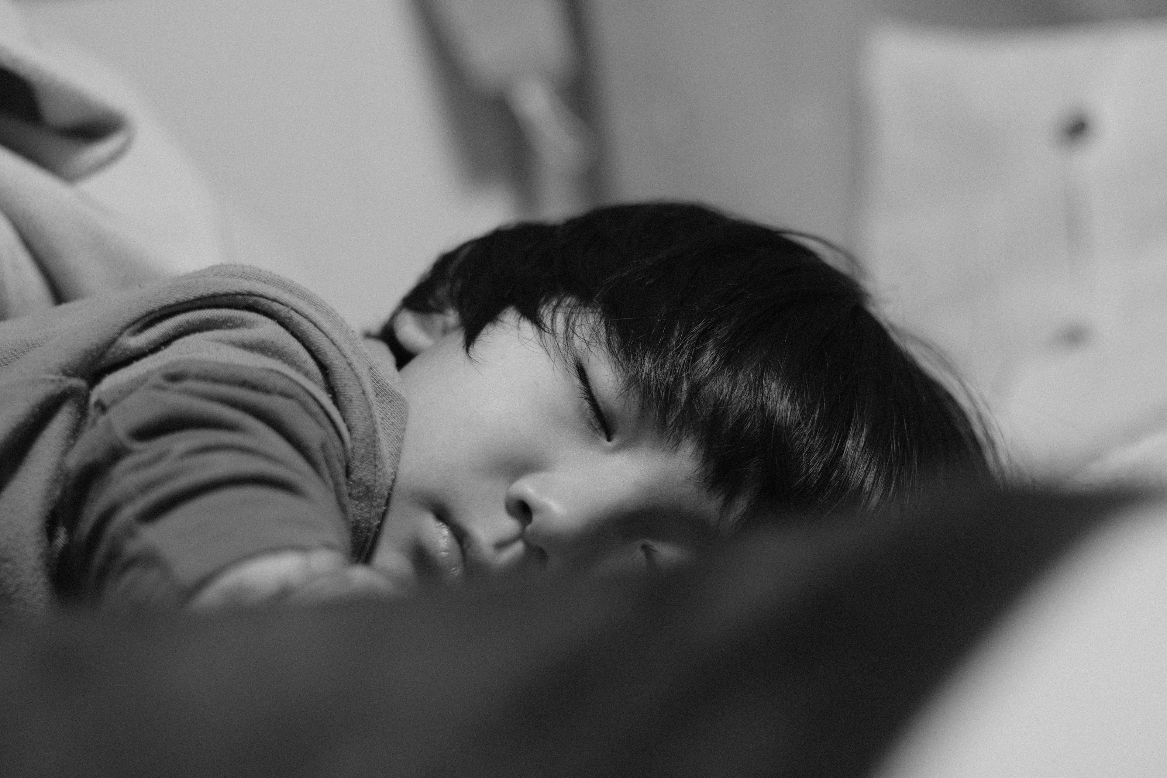 眠っている子供の顔が柔らかい光の中にあり、周囲はぼやけている