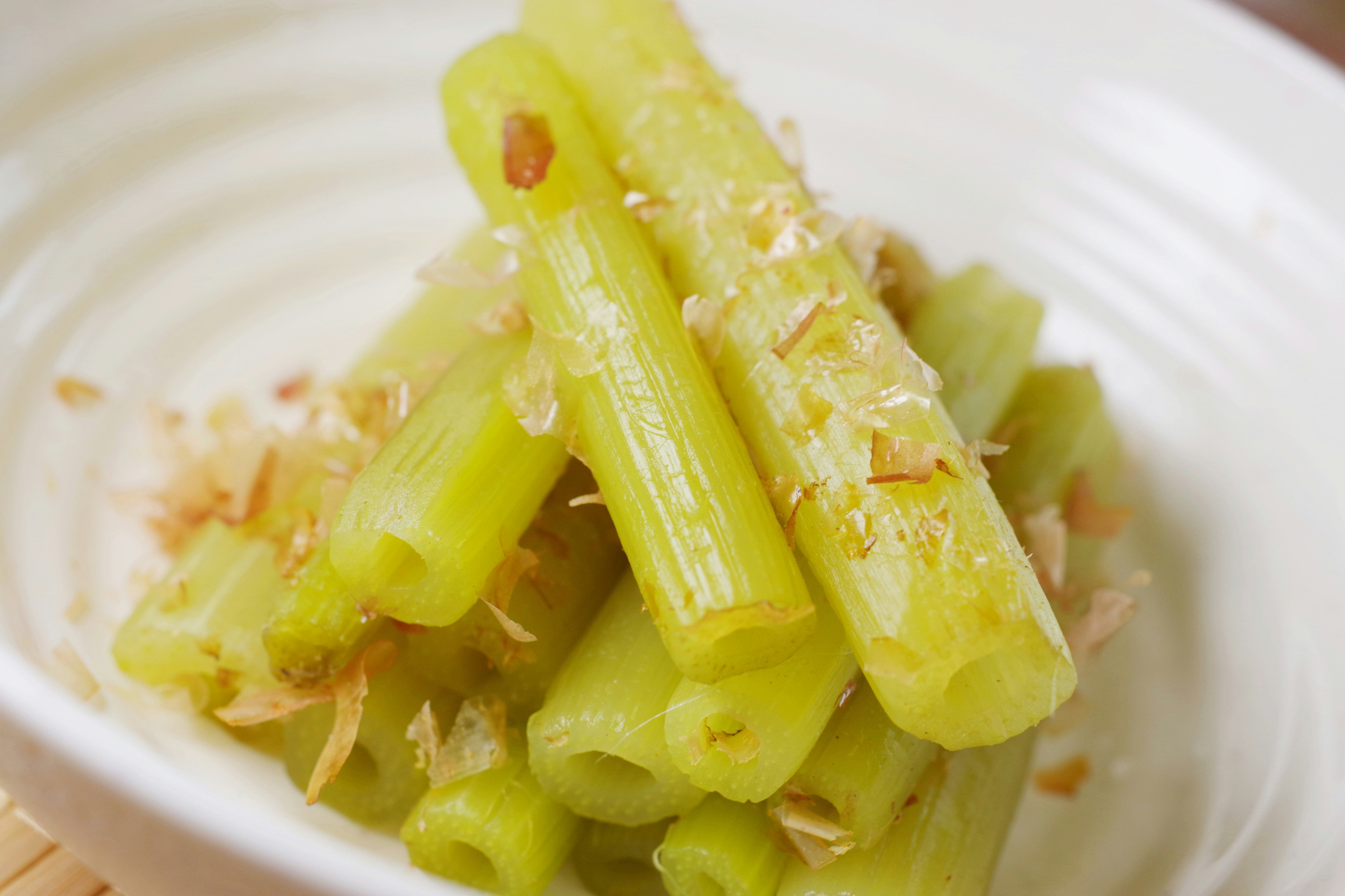 Fresh green celery sticks arranged in a white bowl