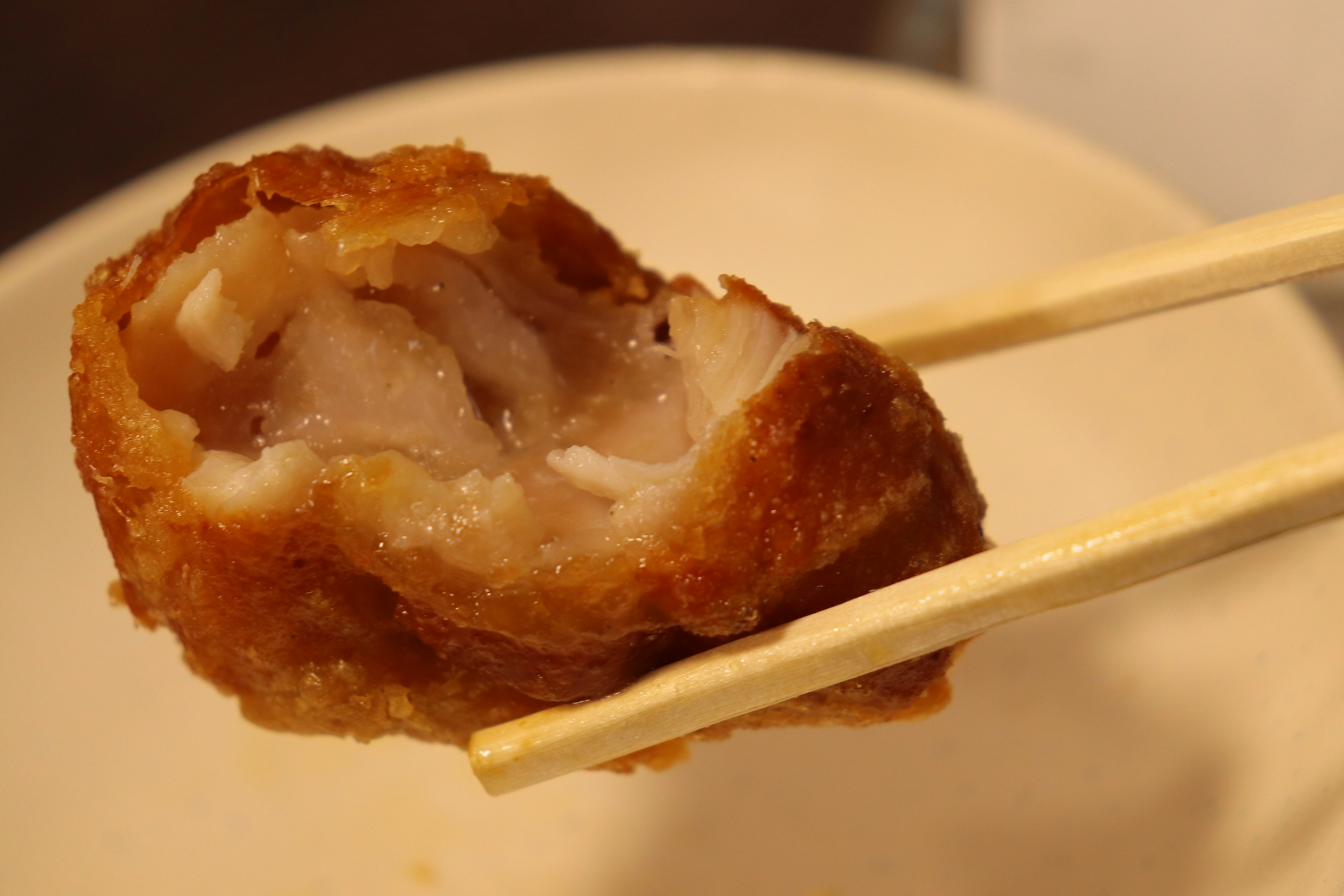 Close-up of a fried dish held with chopsticks showing the inside texture