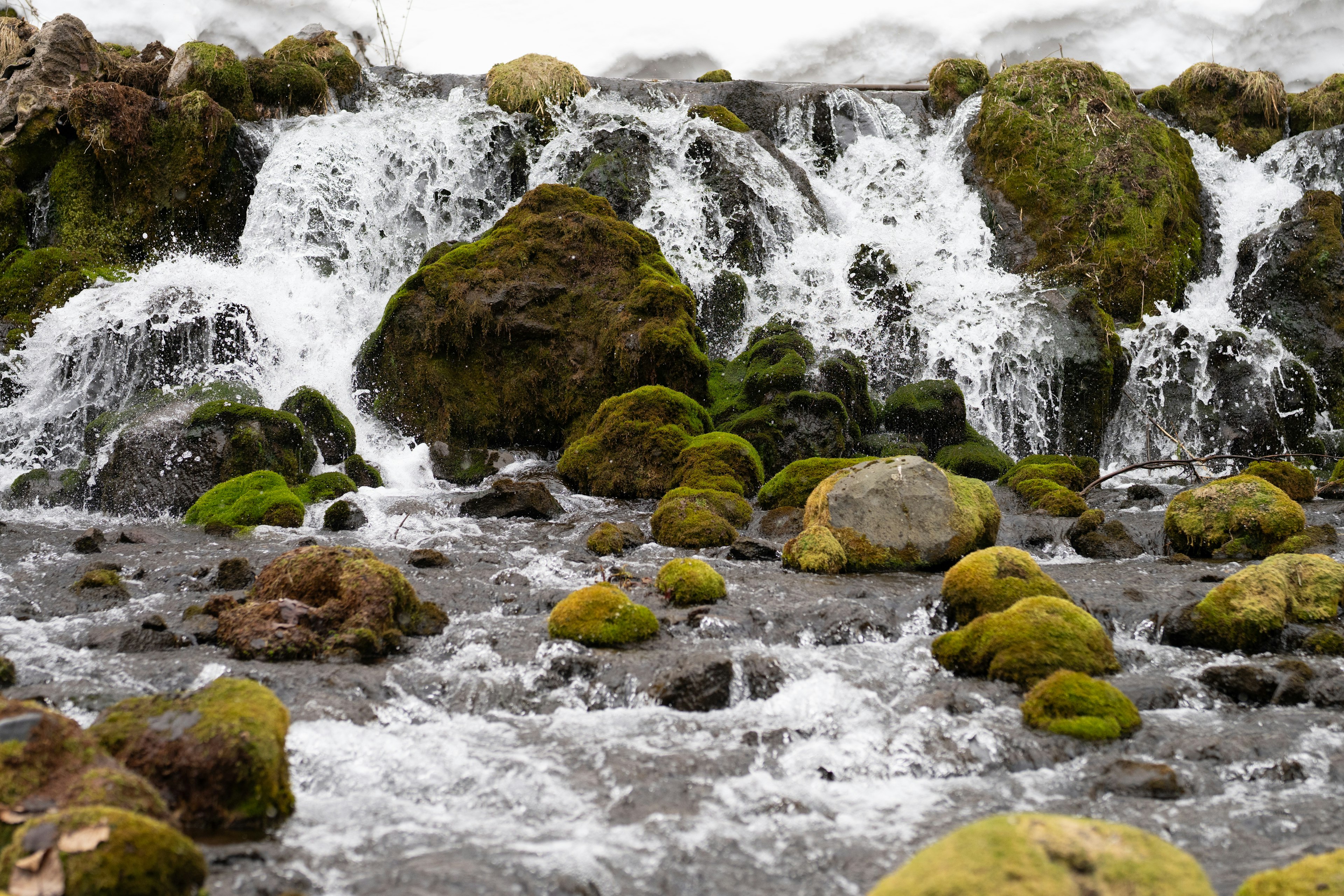 Air terjun indah dengan batu-batu yang ditutupi lumut dan air yang mengalir