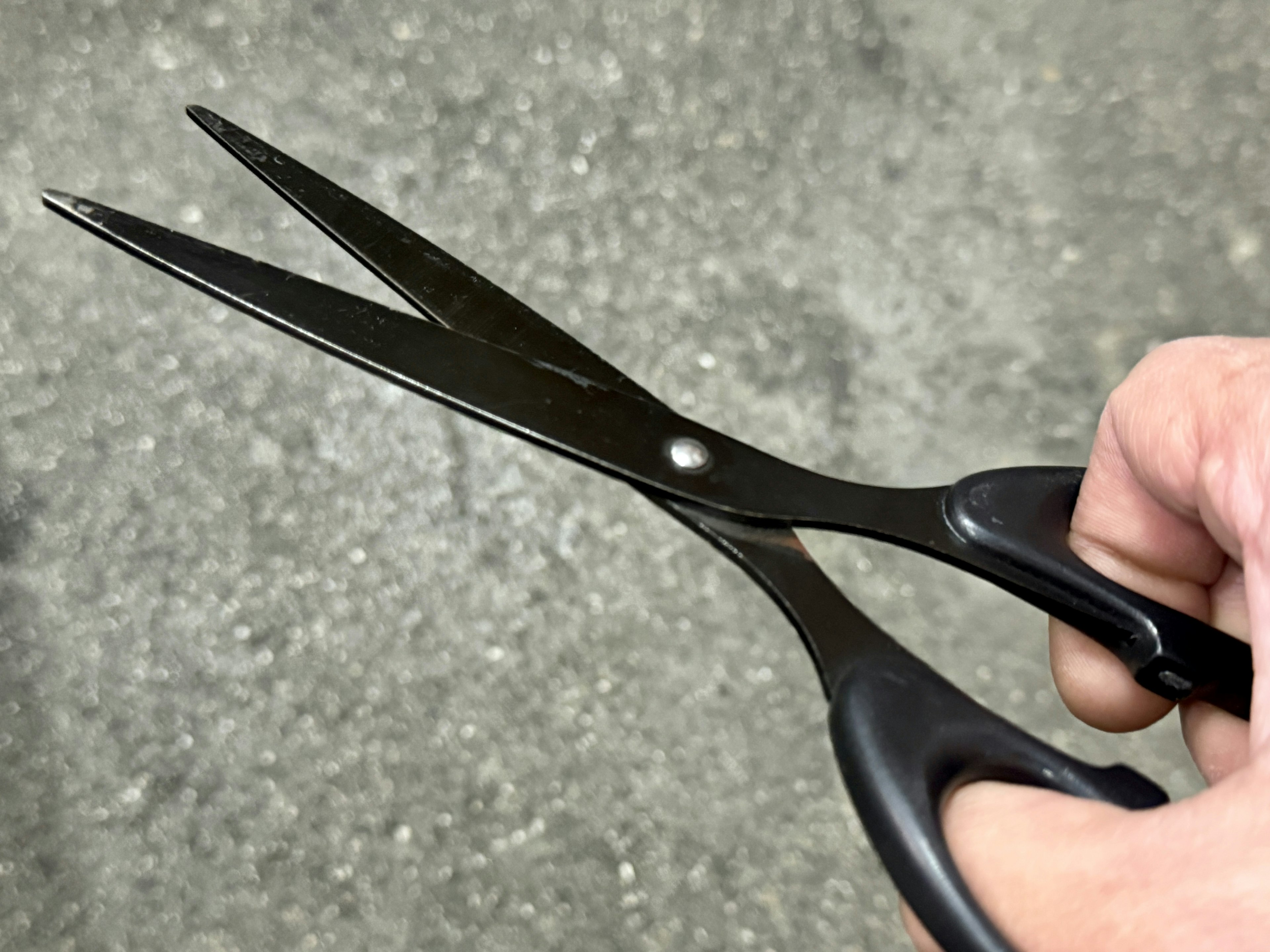 Image of a hand holding black scissors with a simple design