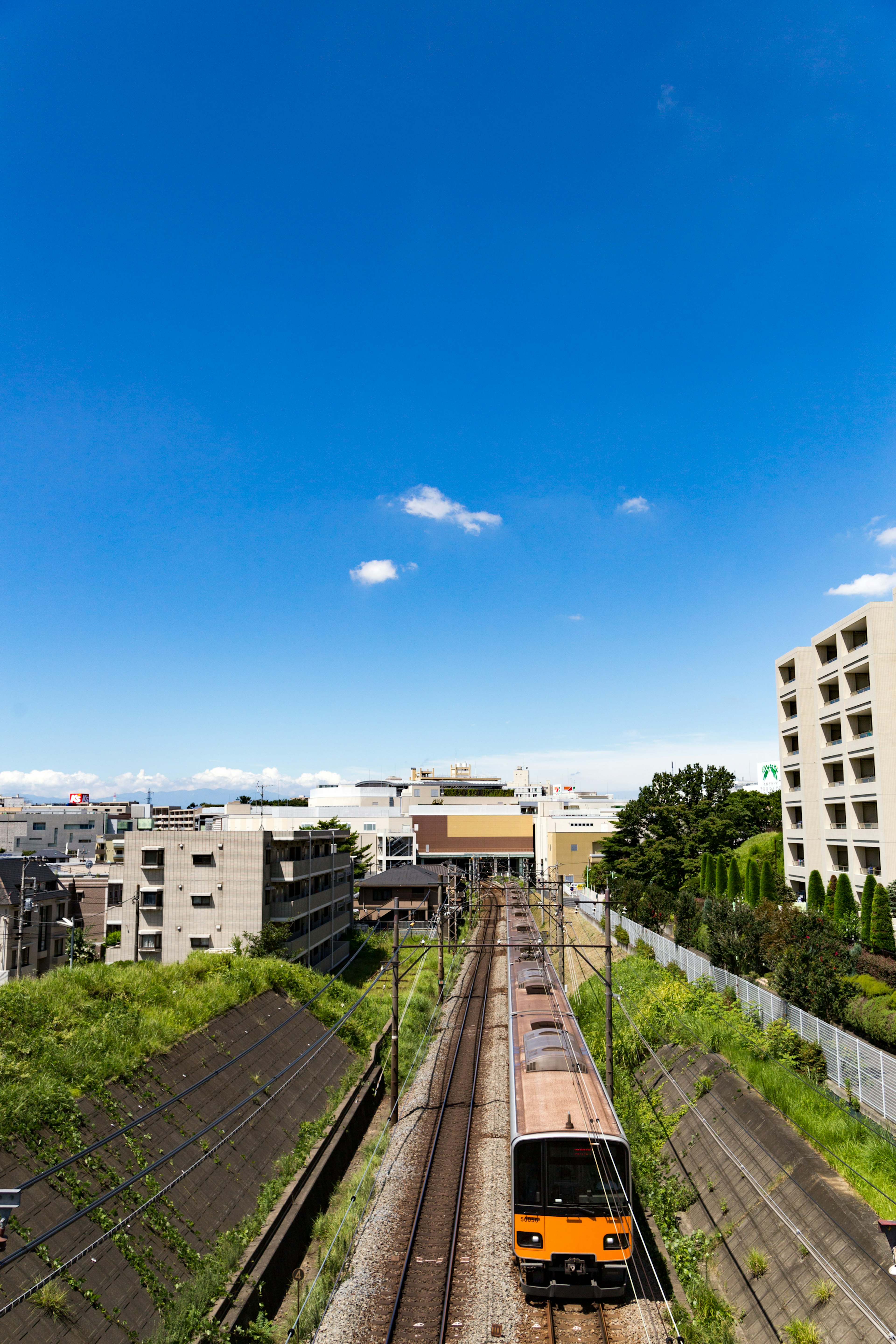 Train running under a blue sky with surrounding buildings