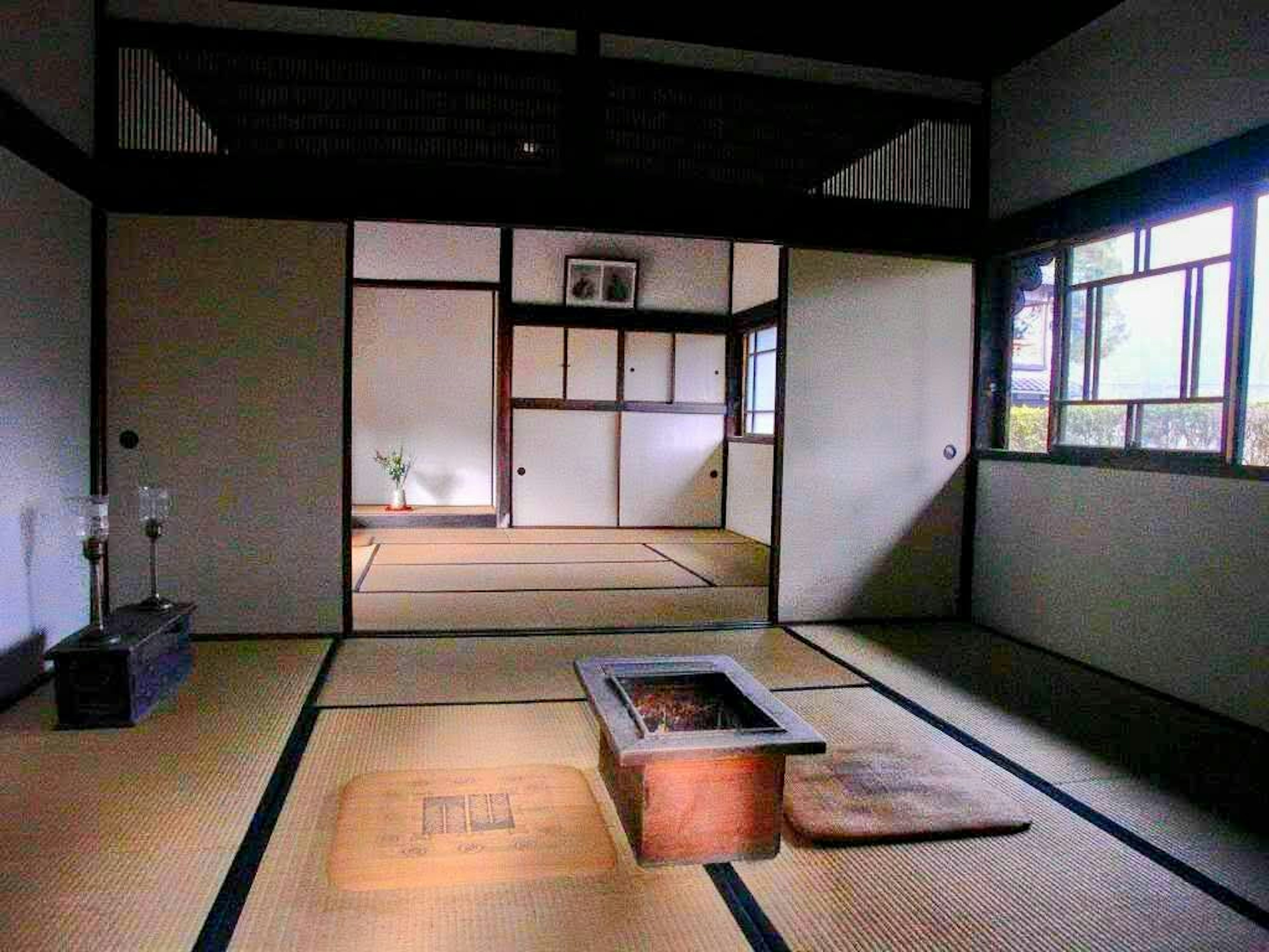 Spacious interior of a traditional Japanese room with tatami flooring and a central irori