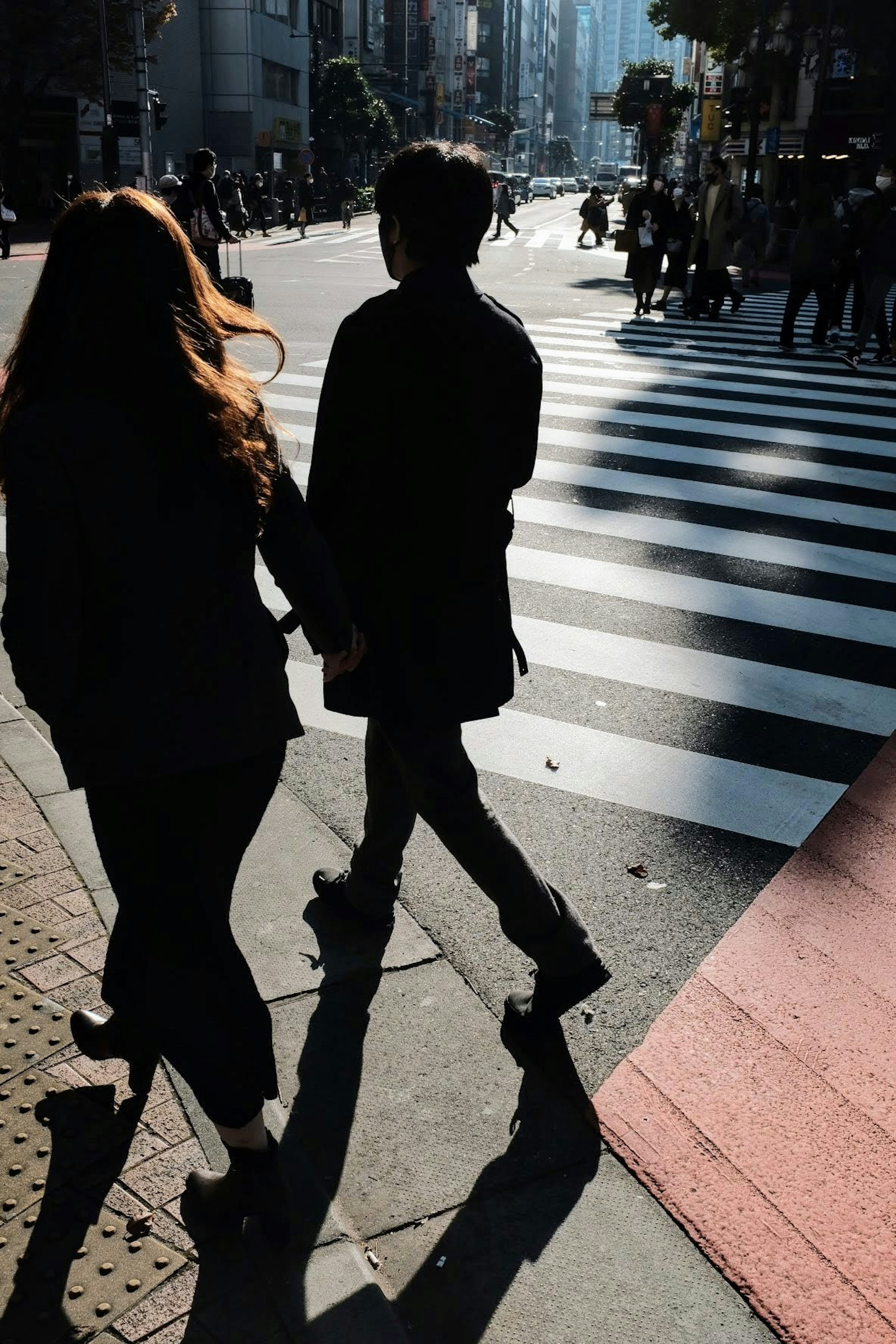 Silhouette d'un couple traversant la rue sur un passage piéton rayé