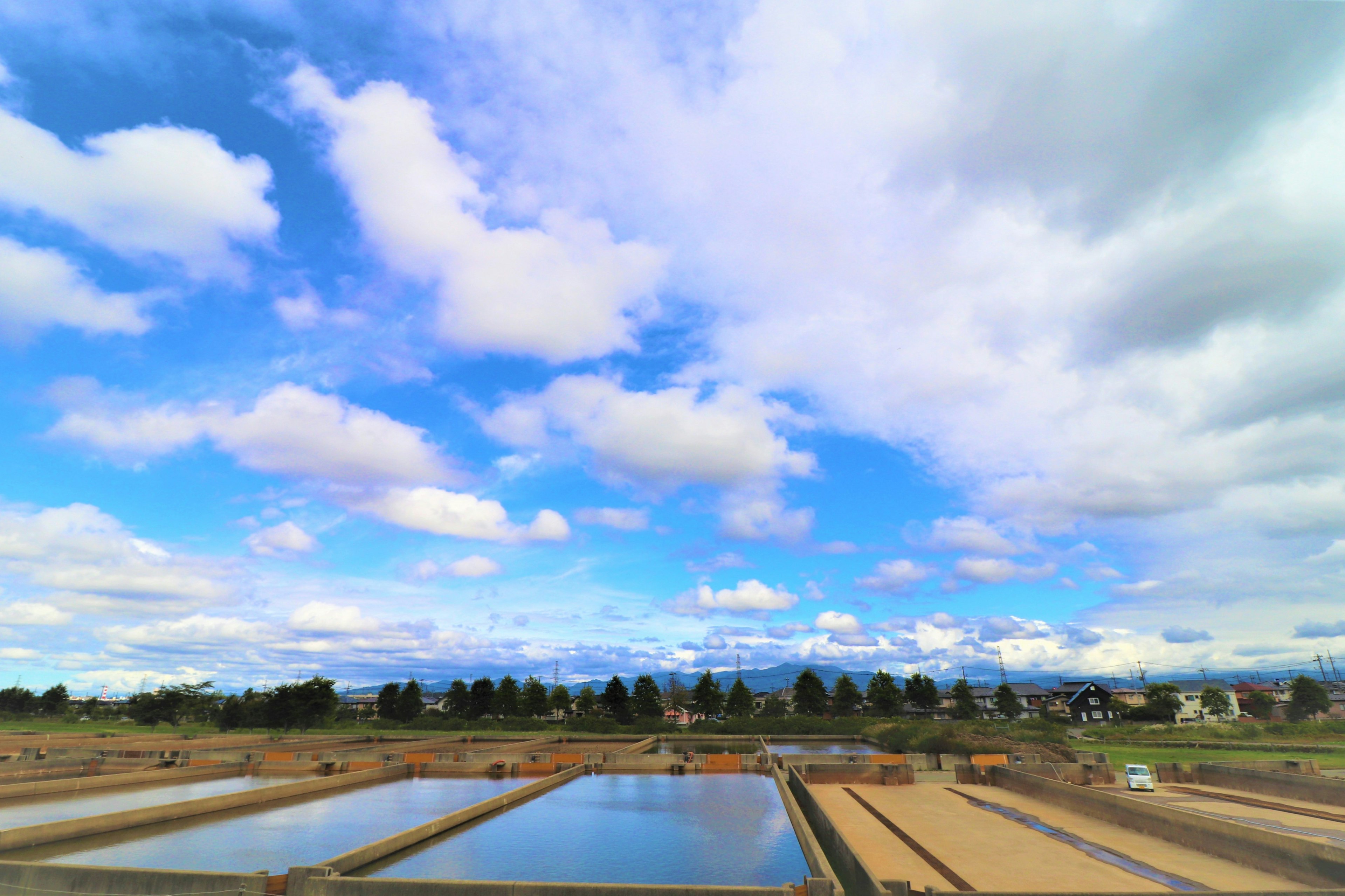 Vue panoramique avec ciel bleu et nuages blancs sur des étangs et des champs