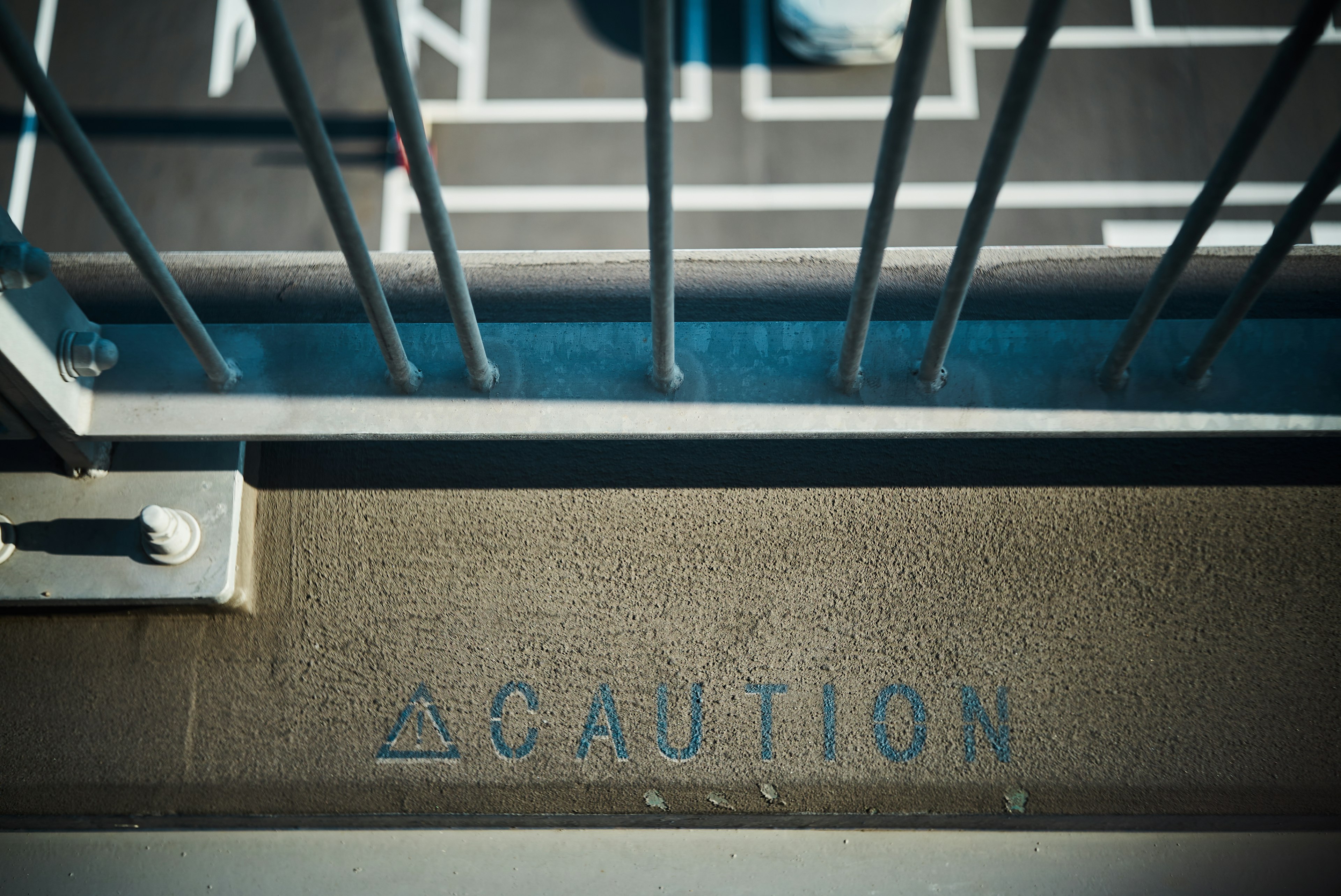 A view of a staircase railing with a caution message on the floor