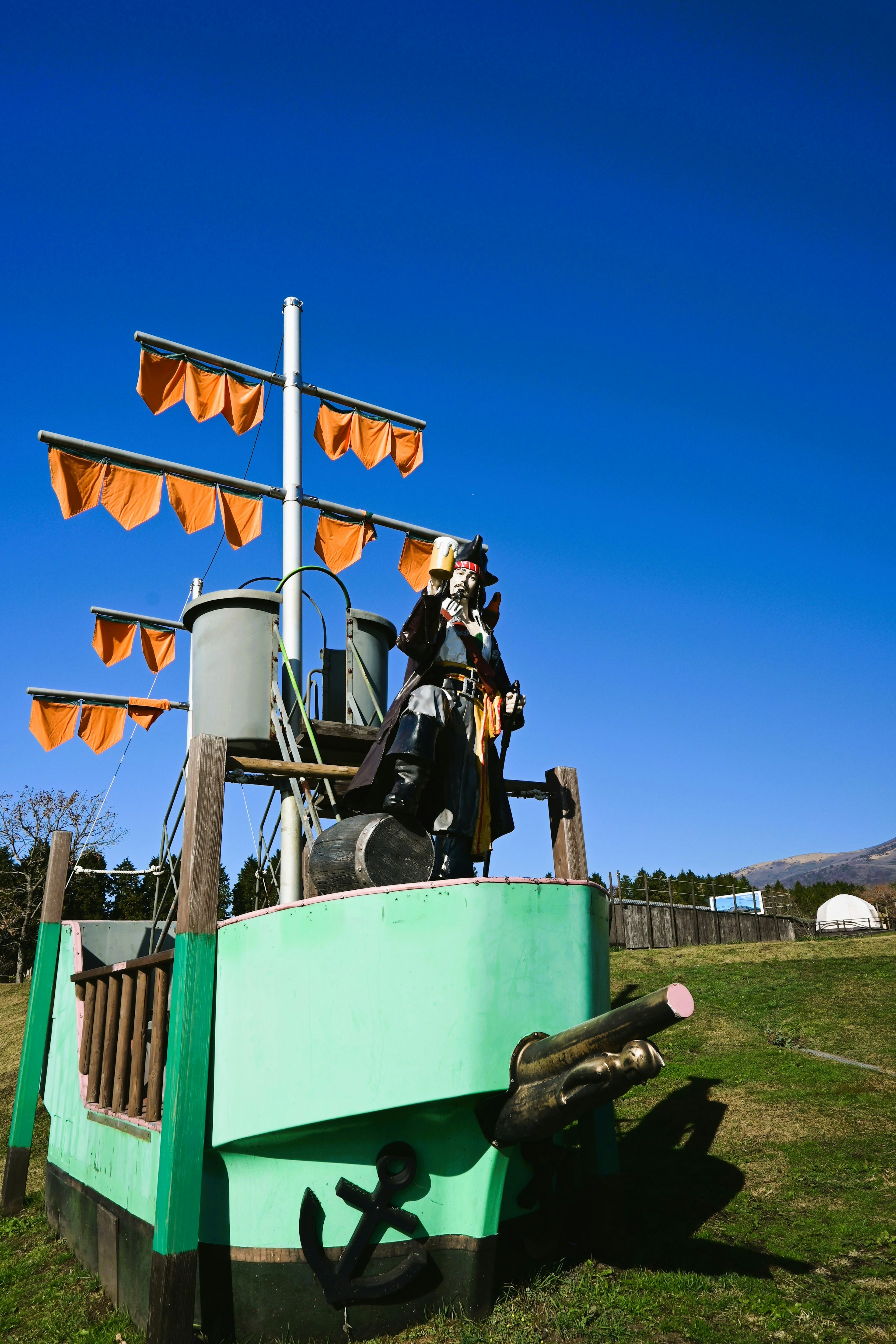 A children's play ship with orange sails and a pirate figure under a blue sky