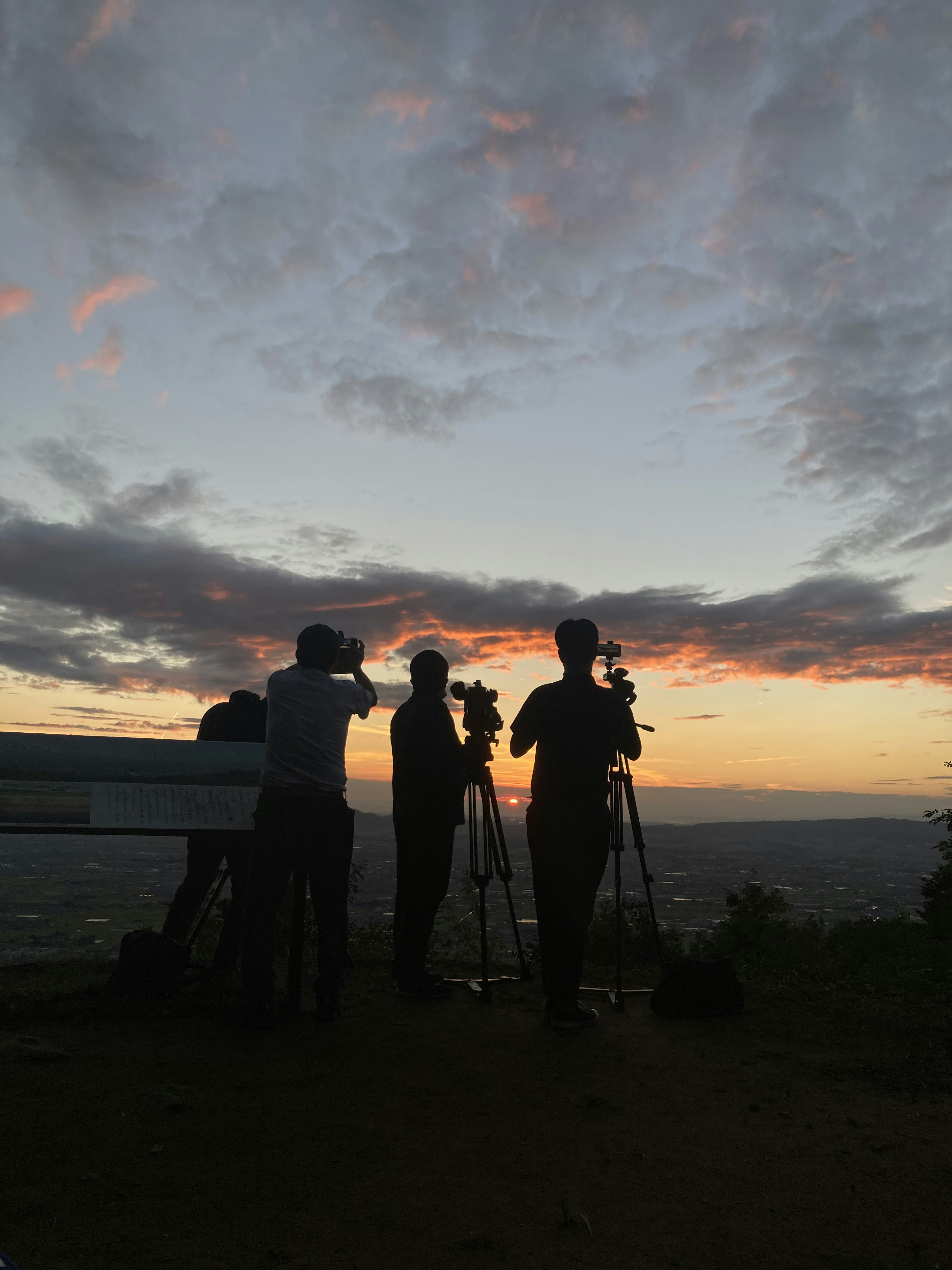 Silhouettes of photographers capturing a sunset with colorful clouds