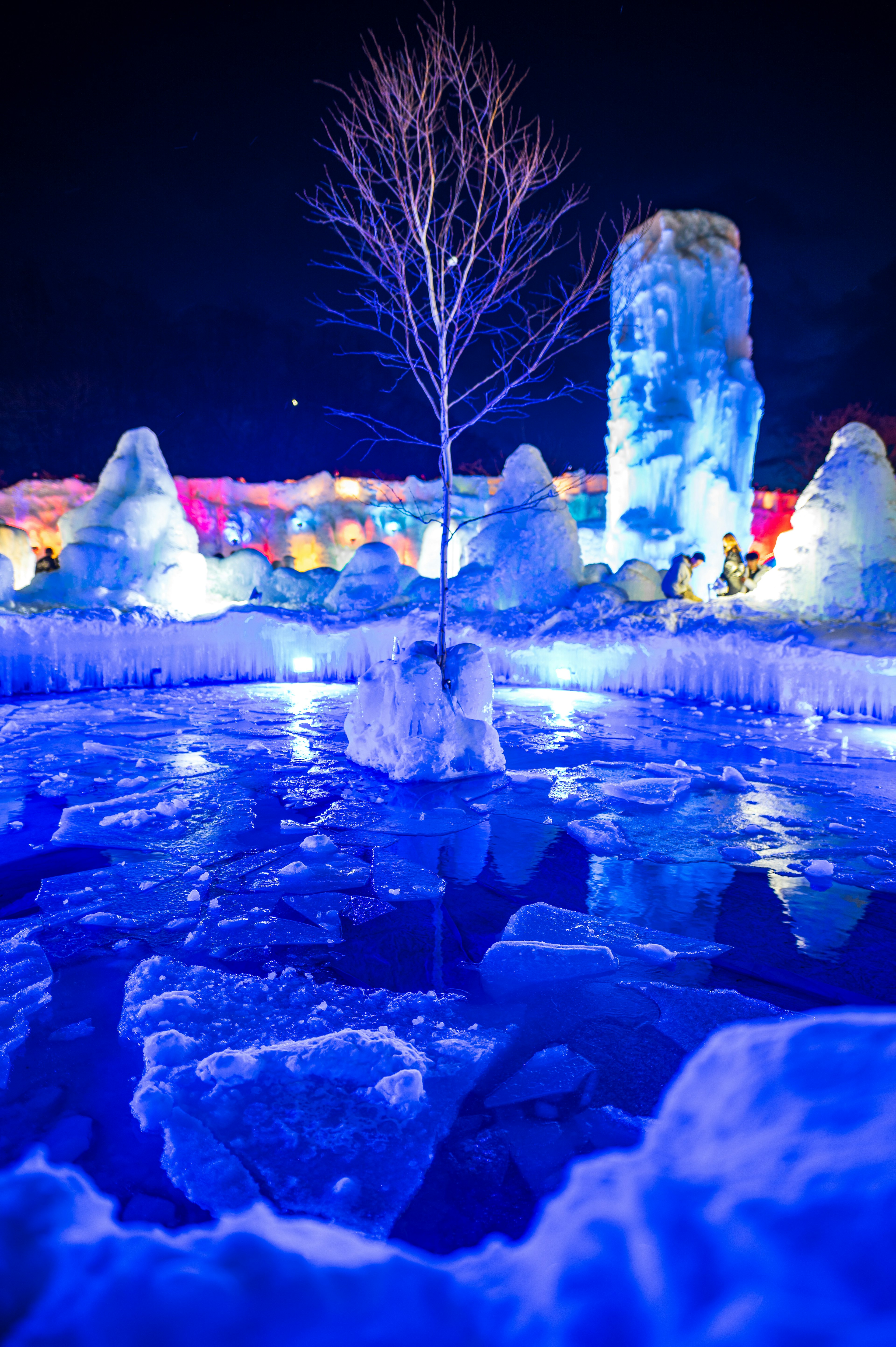 Escena de formaciones de hielo azules y un estanque congelado con un árbol