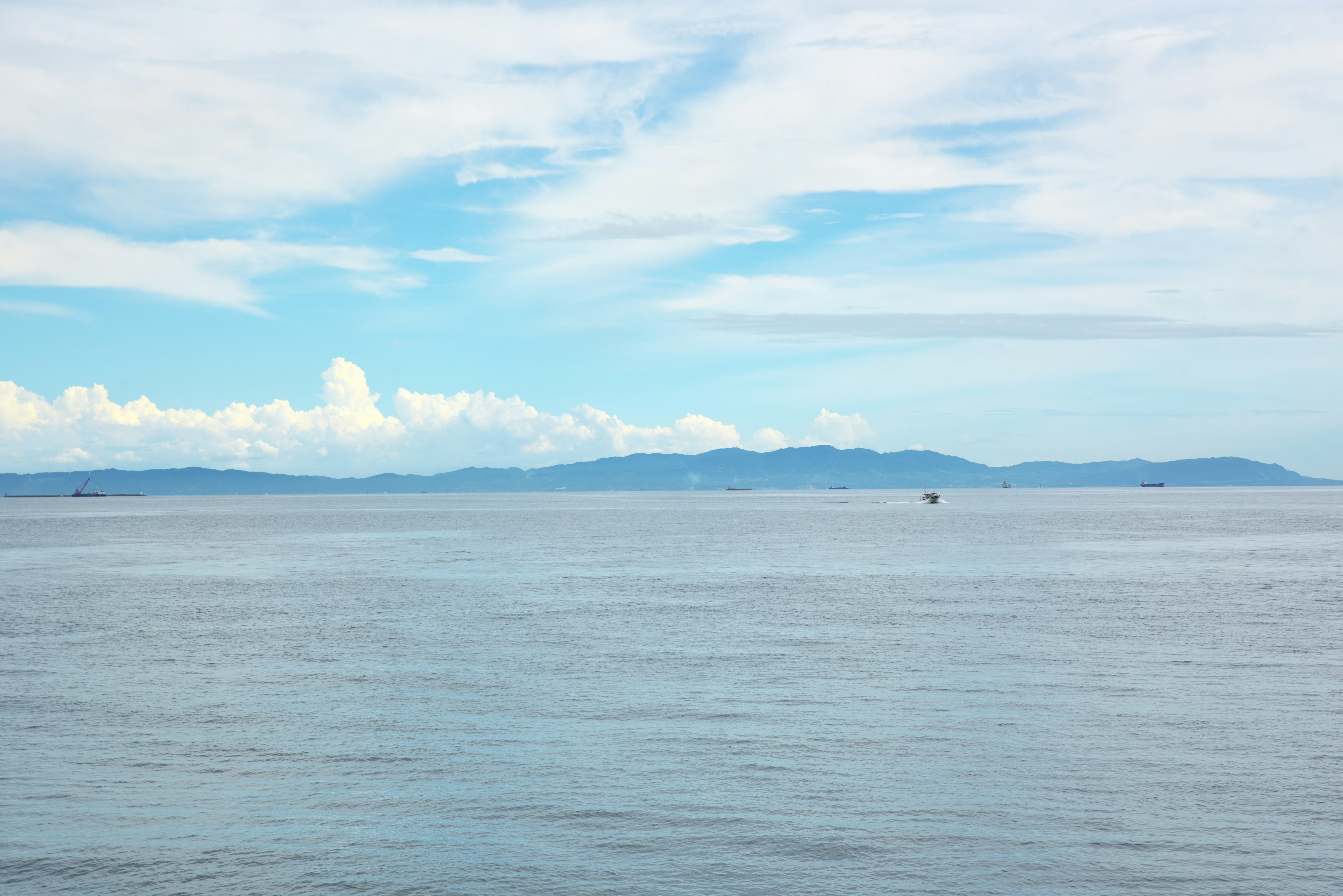 Blue ocean and sky landscape with distant mountains