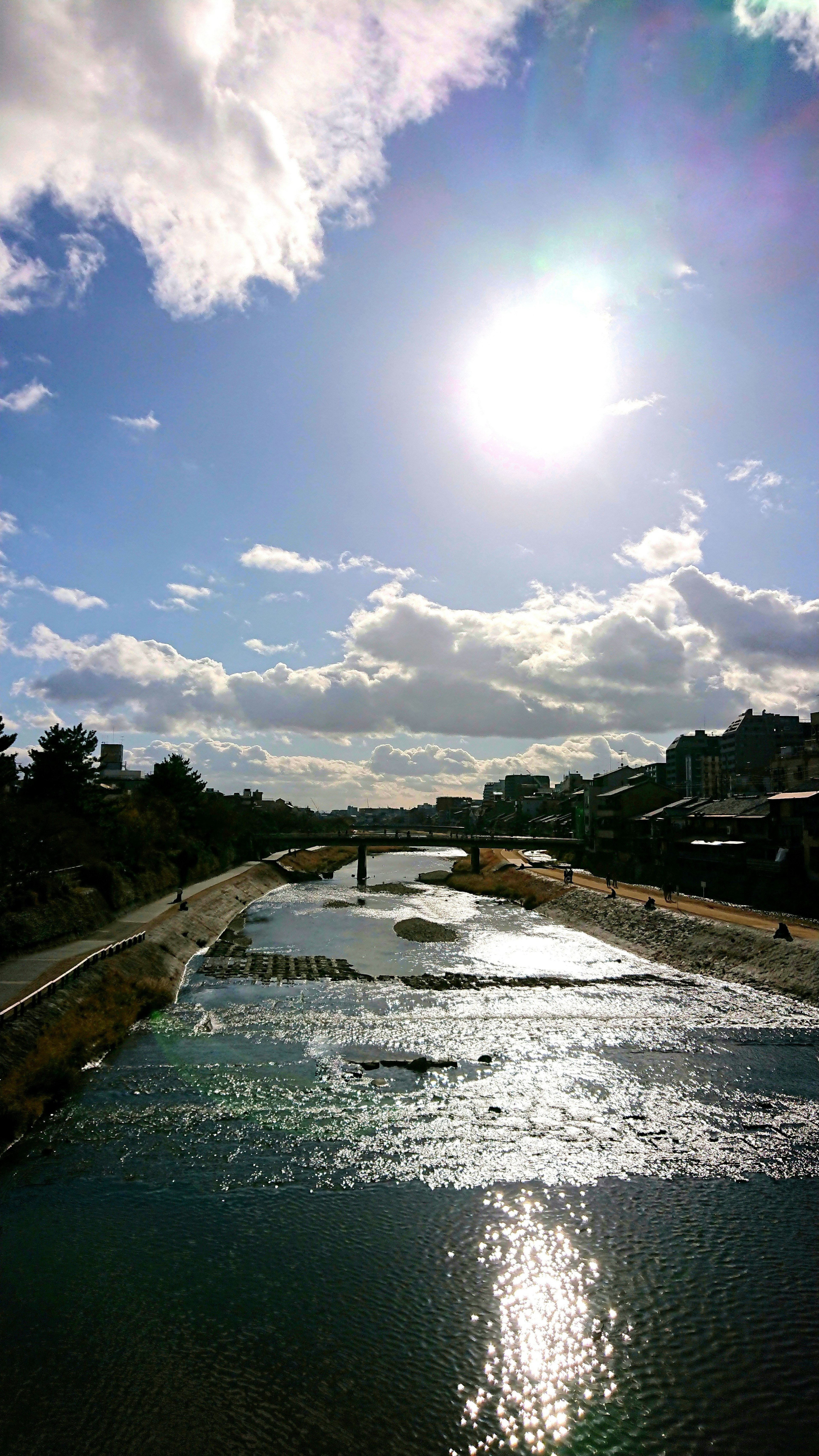 Paysage de rivière sous un ciel bleu avec des nuages soleil brillant se reflétant sur la surface de l'eau