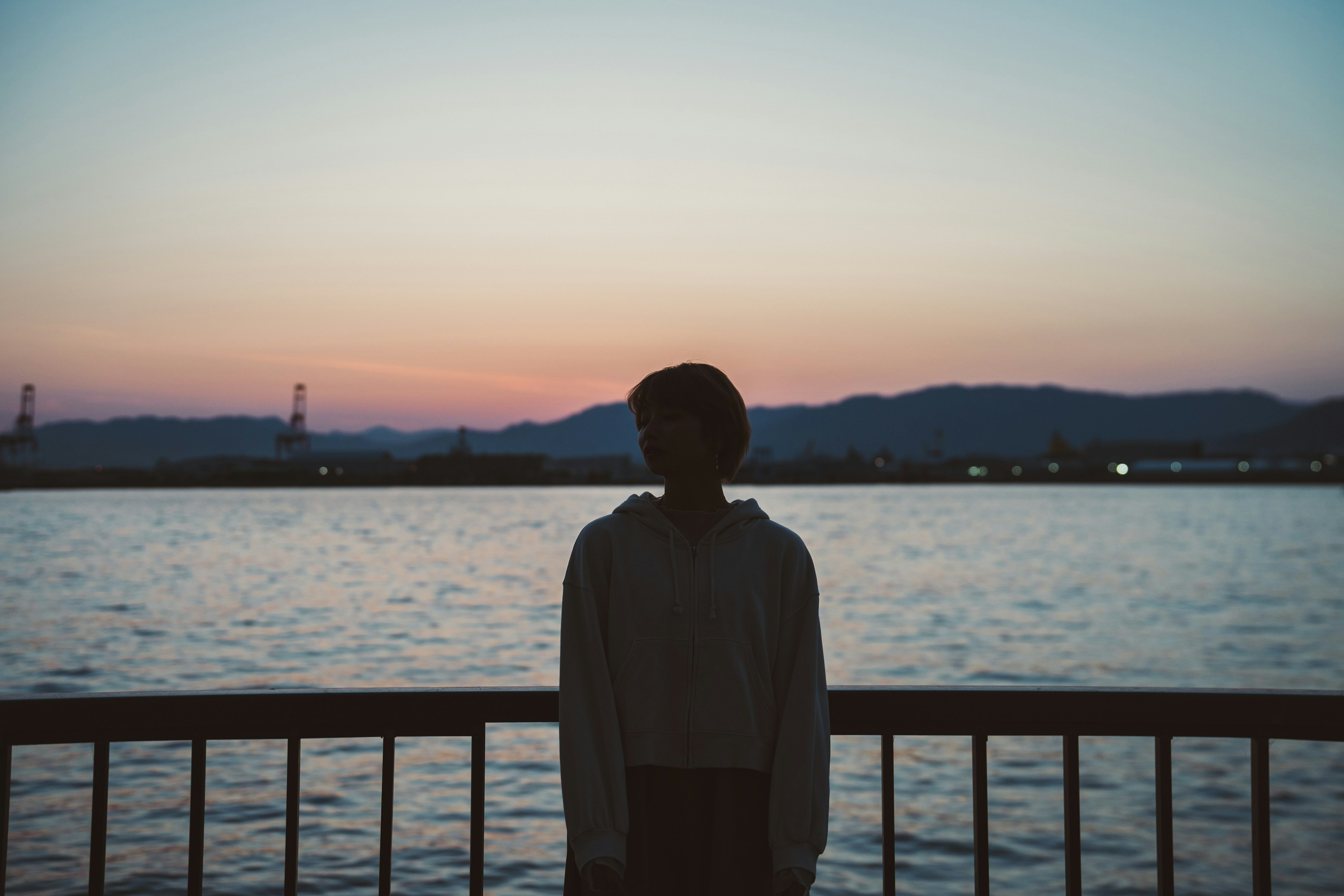 Silhouette einer Person, die am Wasser bei Sonnenuntergang steht