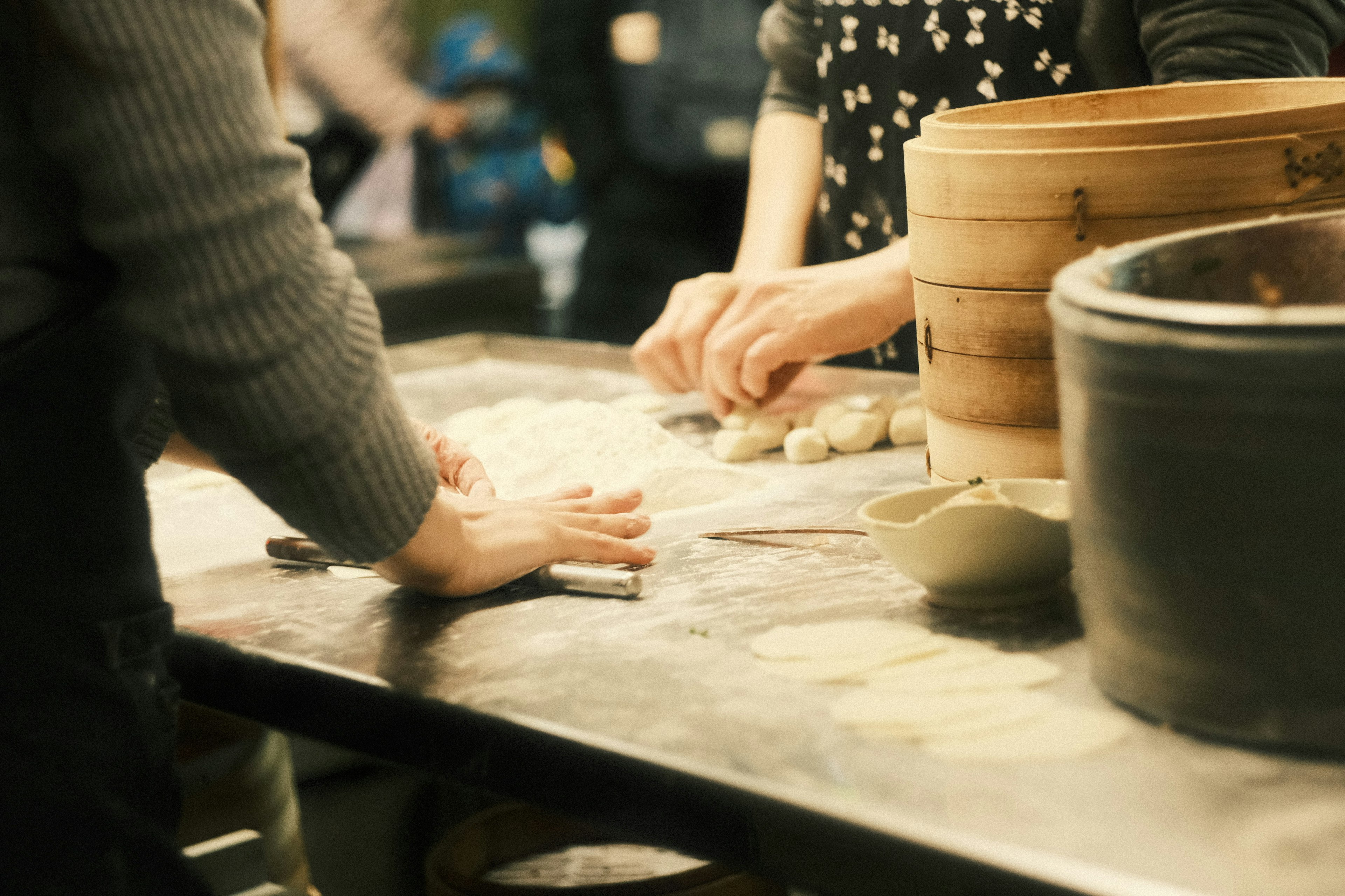 Manos de personas preparando comida en una mesa con varios ingredientes