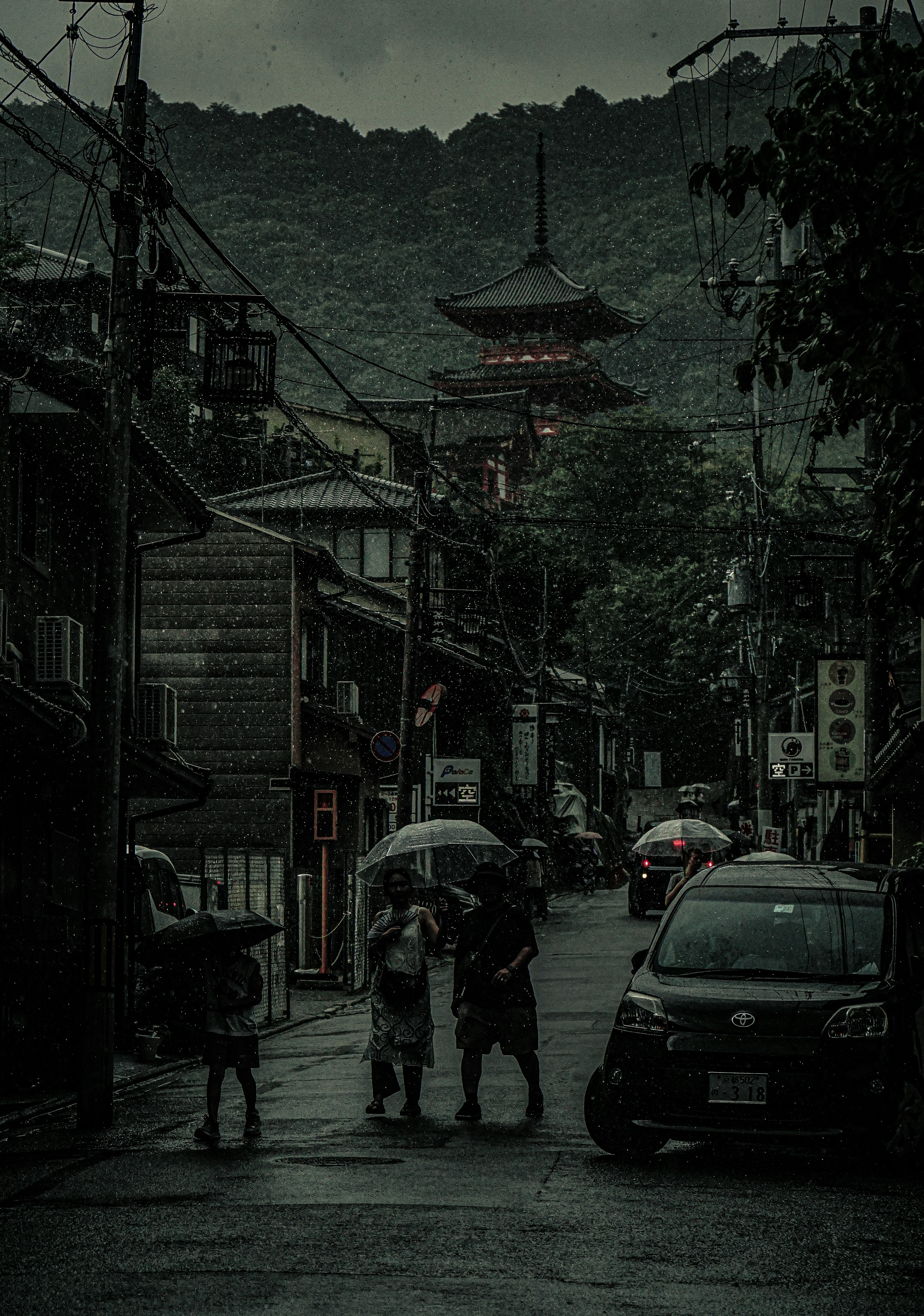 Personas caminando bajo la lluvia con una torre en el fondo montañoso