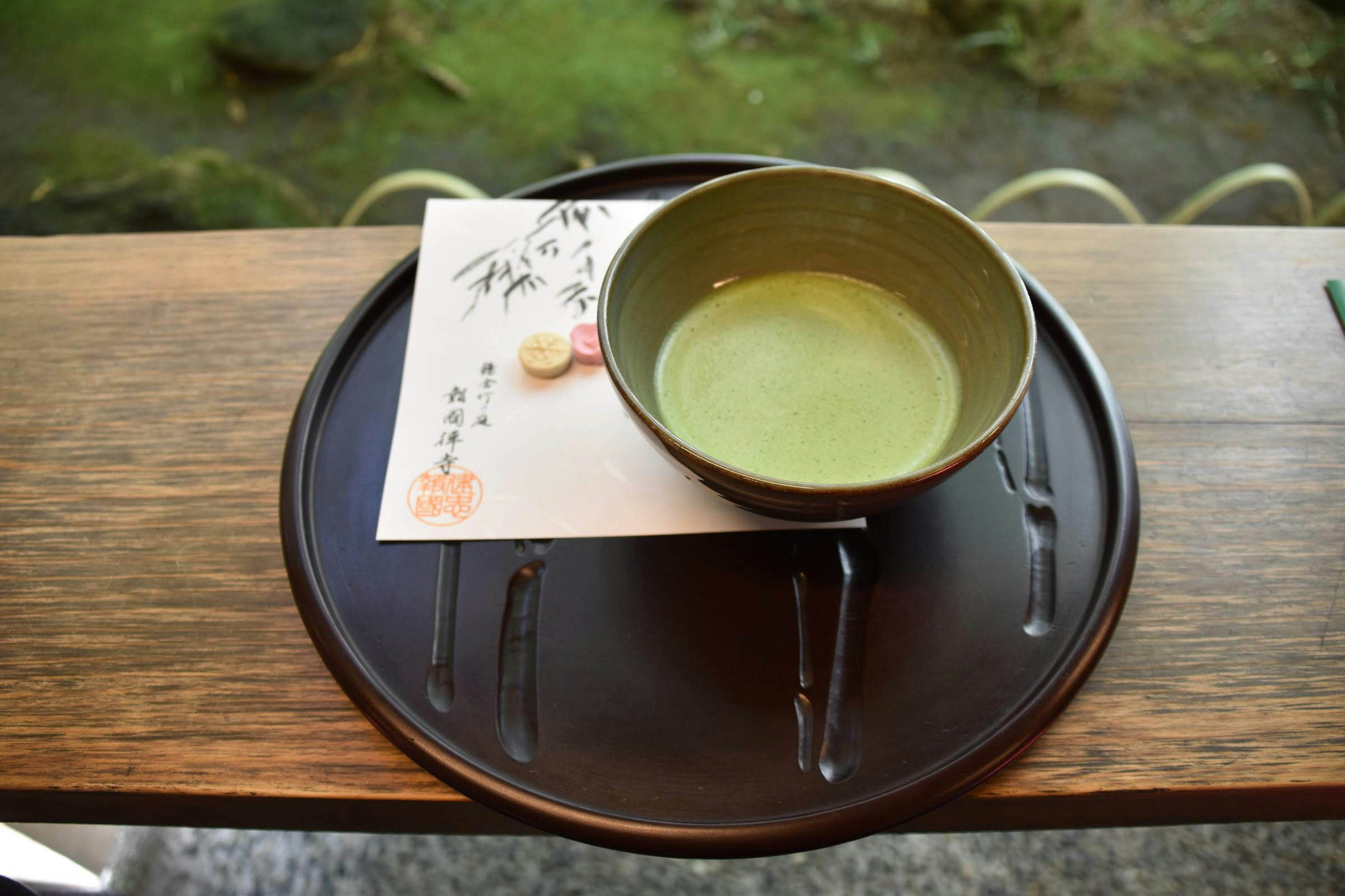 A bowl of green tea and a Japanese sweet on a tray