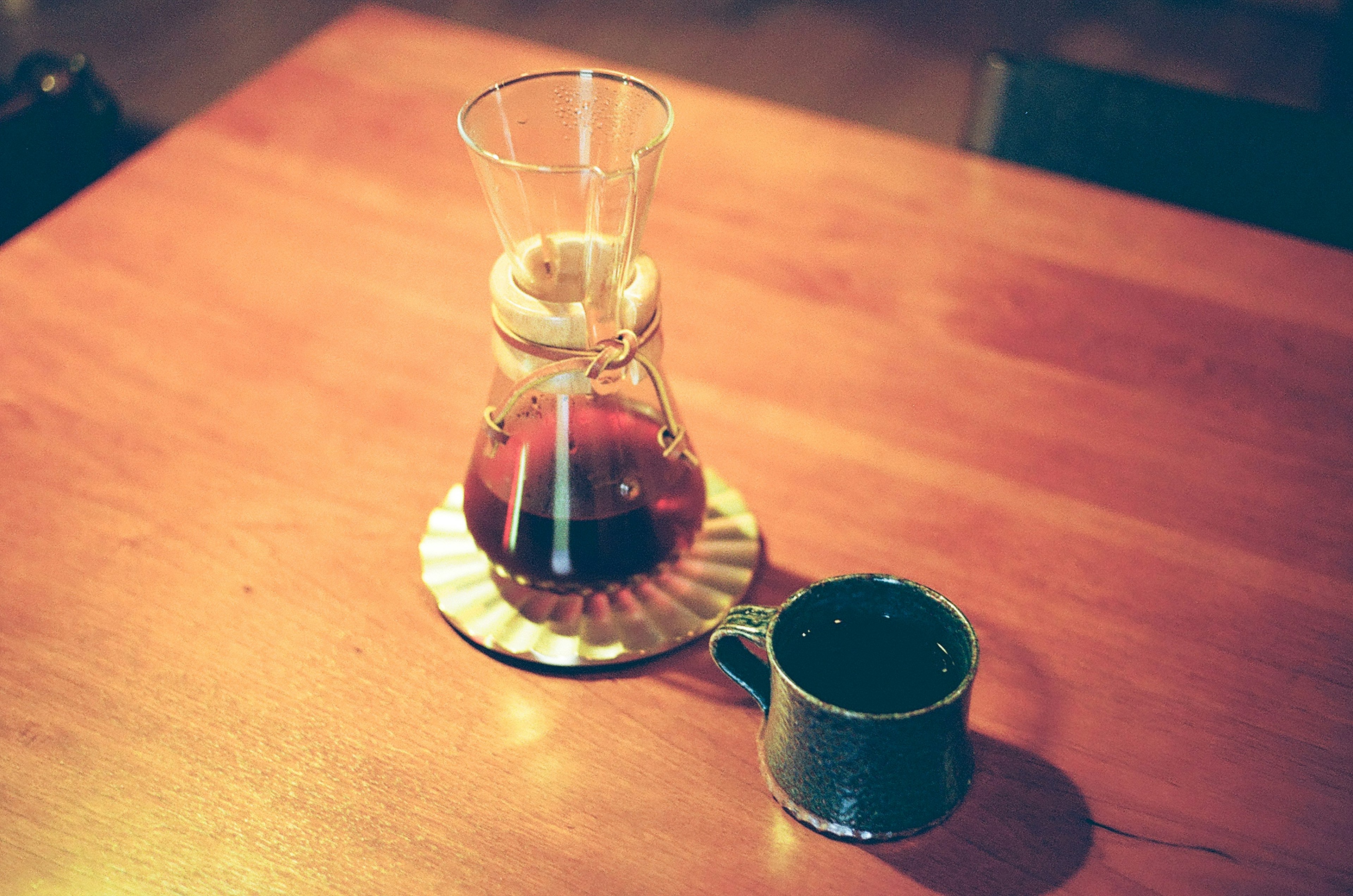 A coffee maker and cup placed on a wooden table