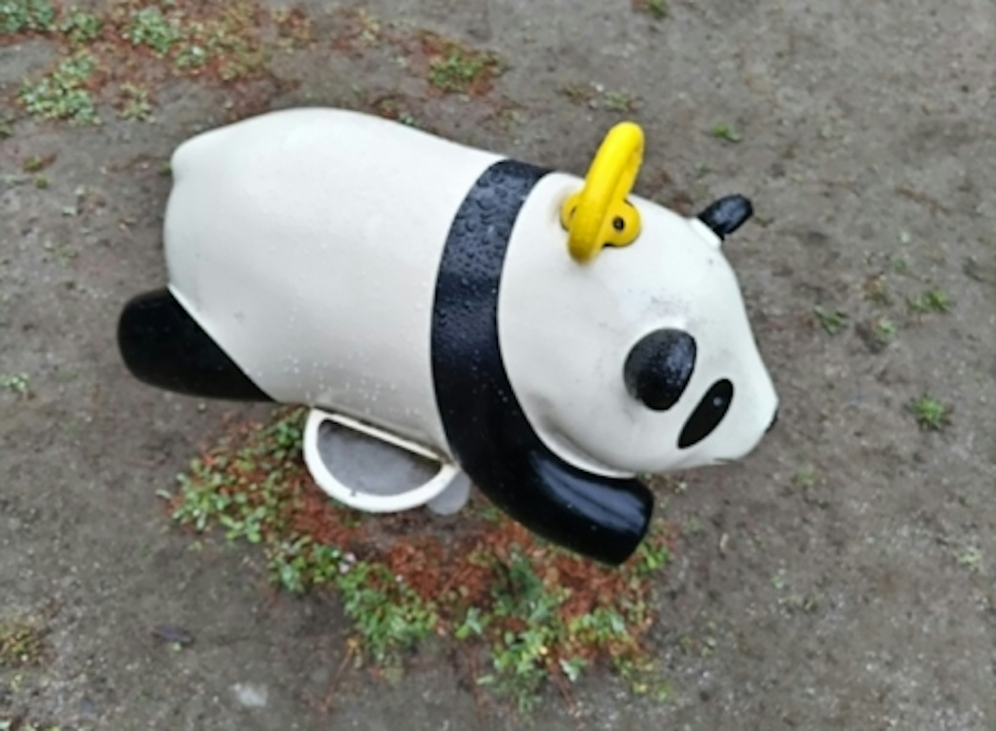 Attrezzatura da gioco a forma di panda in un parco con colori bianco e nero e un anello giallo