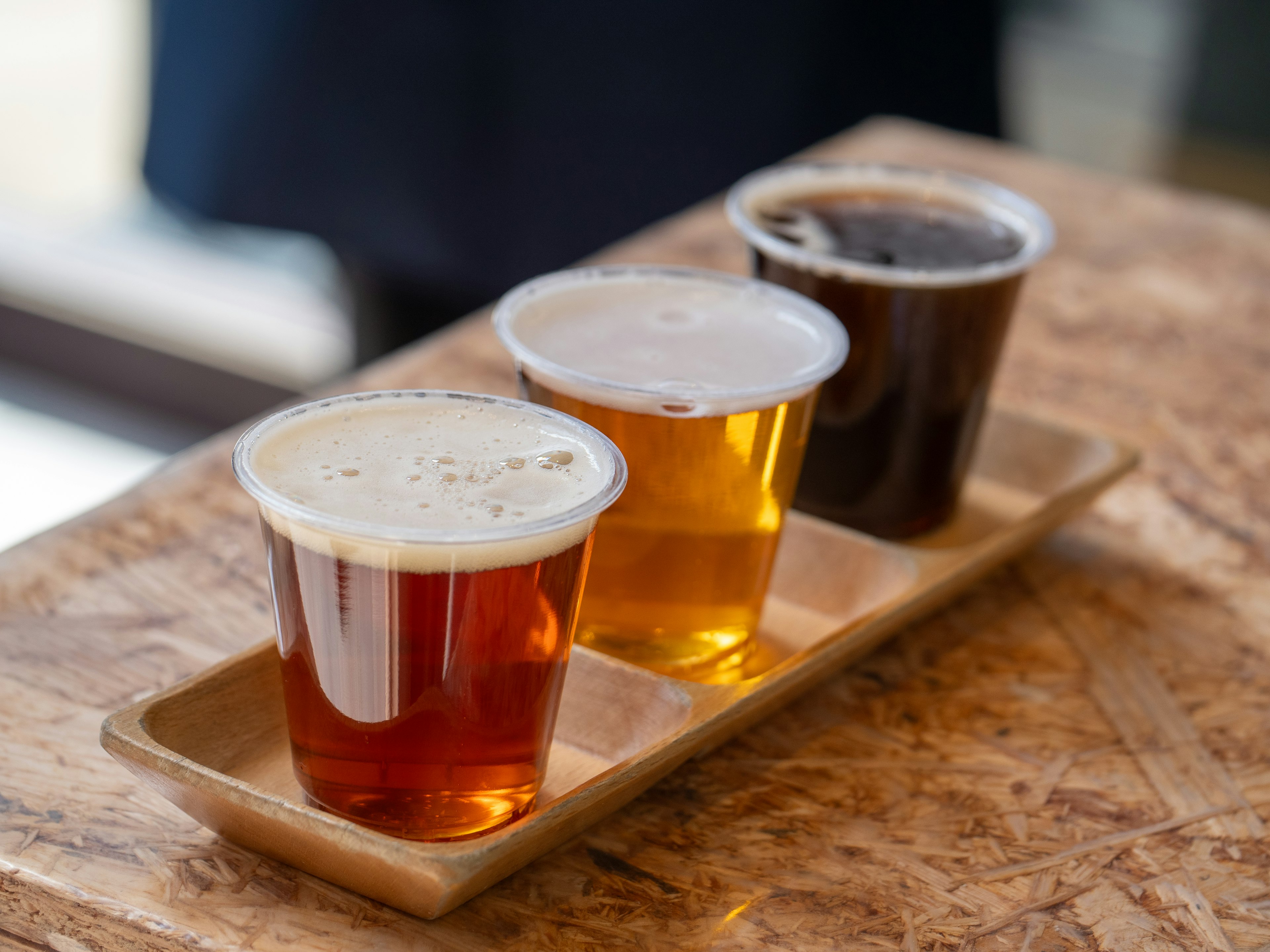 Three beer tasting cups arranged on a wooden tray