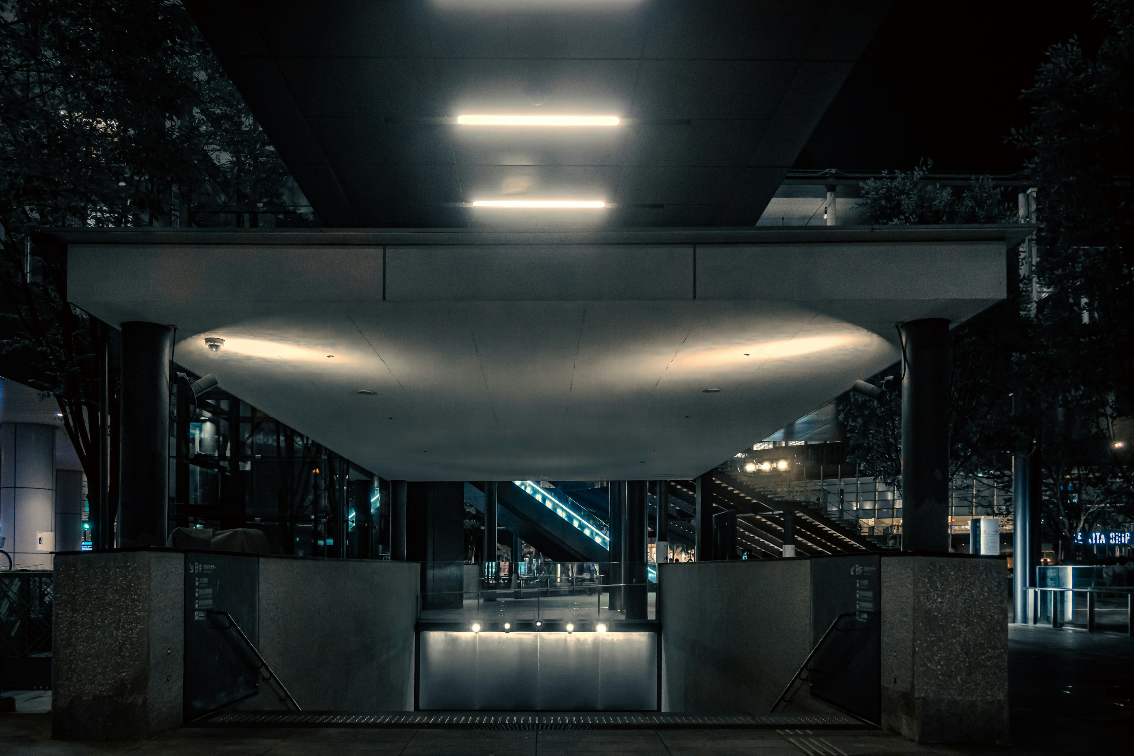 Entrada de un edificio moderno por la noche con iluminación brillante y diseño minimalista