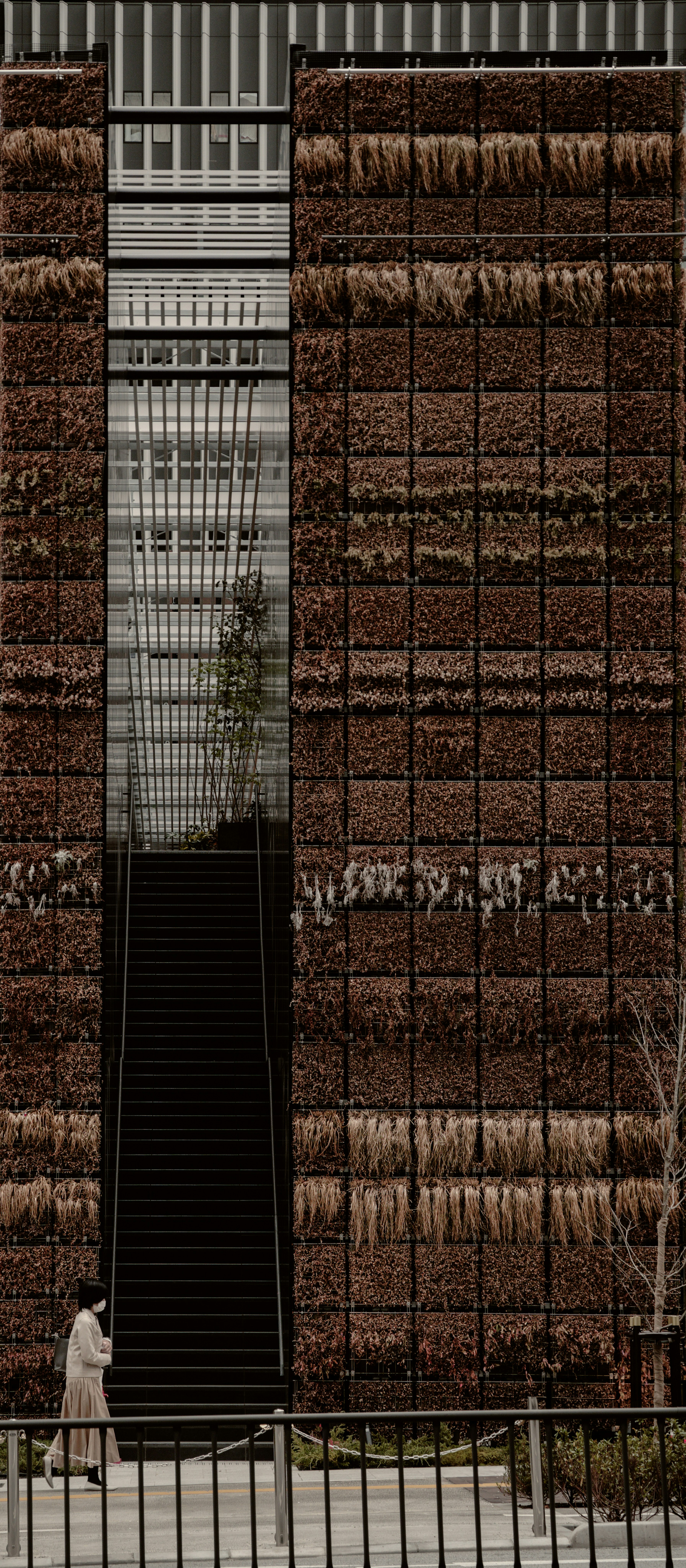 A modern architectural facade of a tall building featuring intricate textures and visible stairs