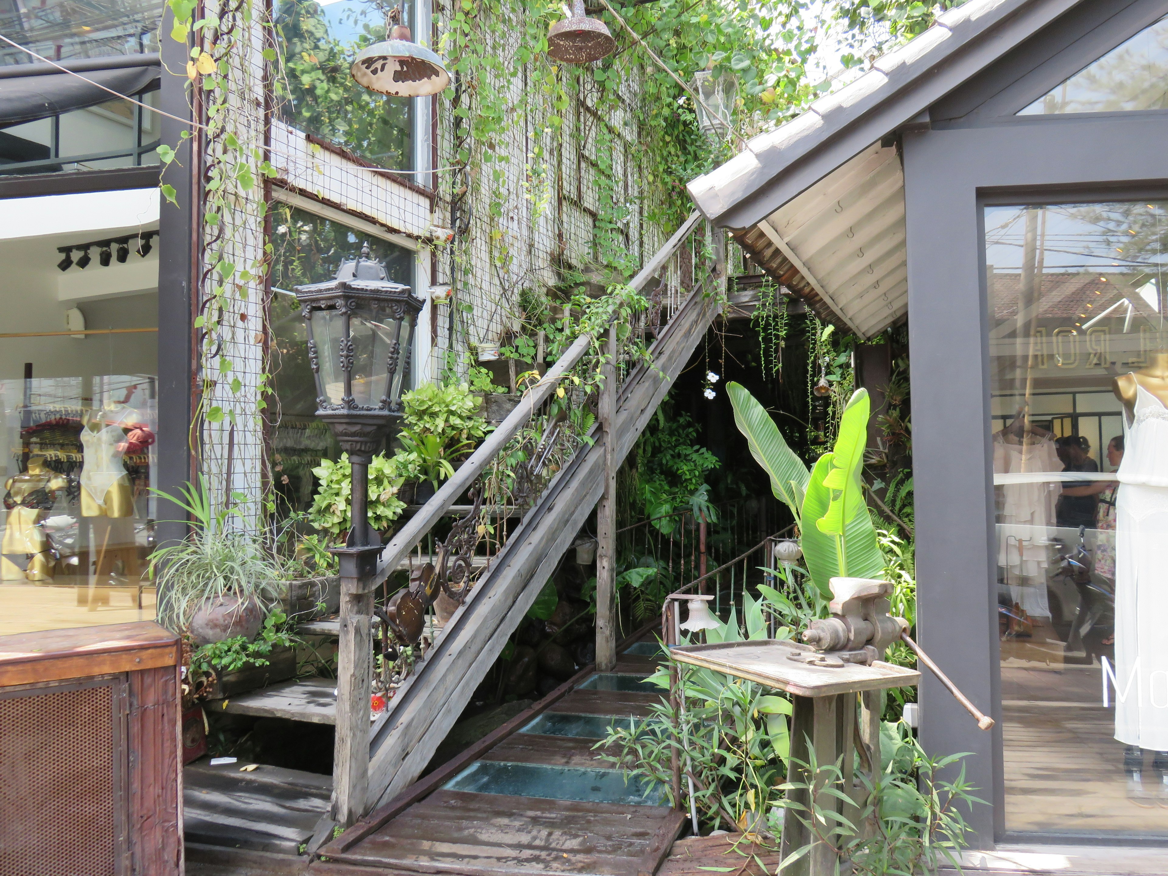 Exterior of a cafe with a staircase surrounded by greenery