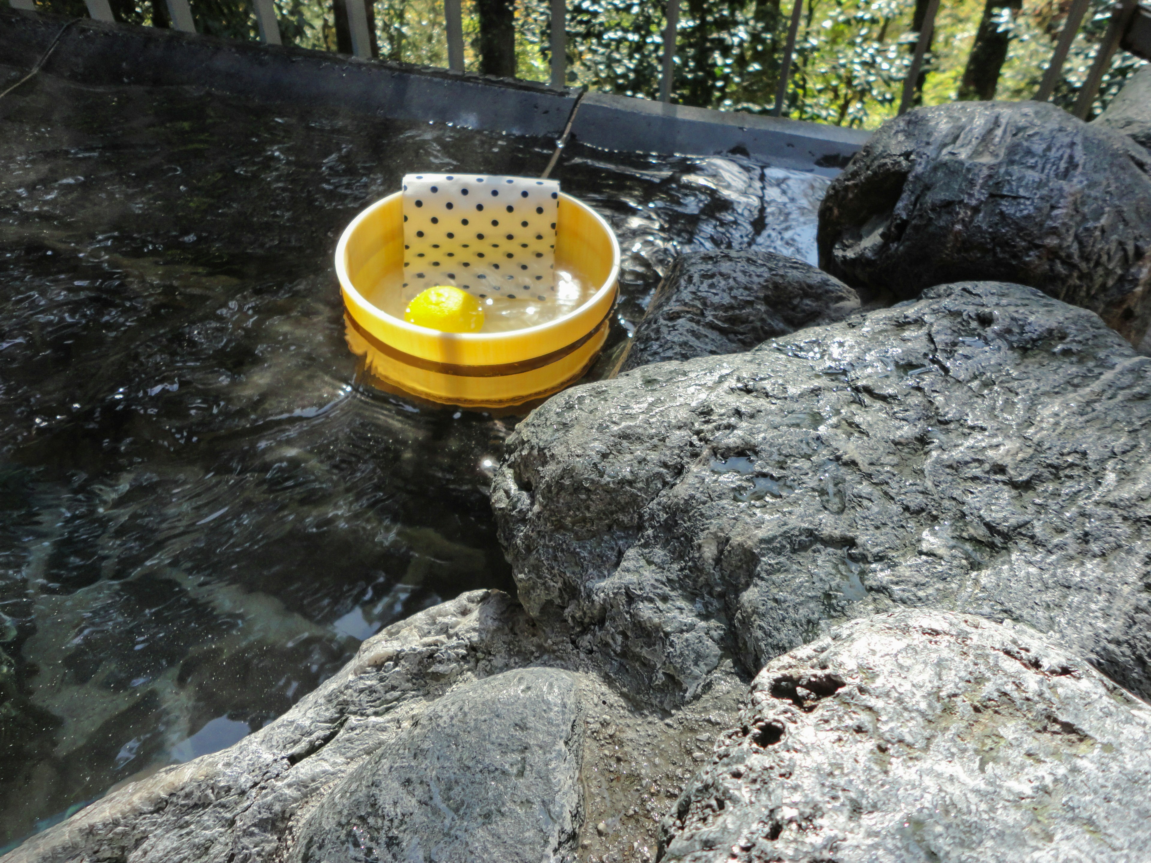 Seau jaune flottant sur l'eau à côté de rochers