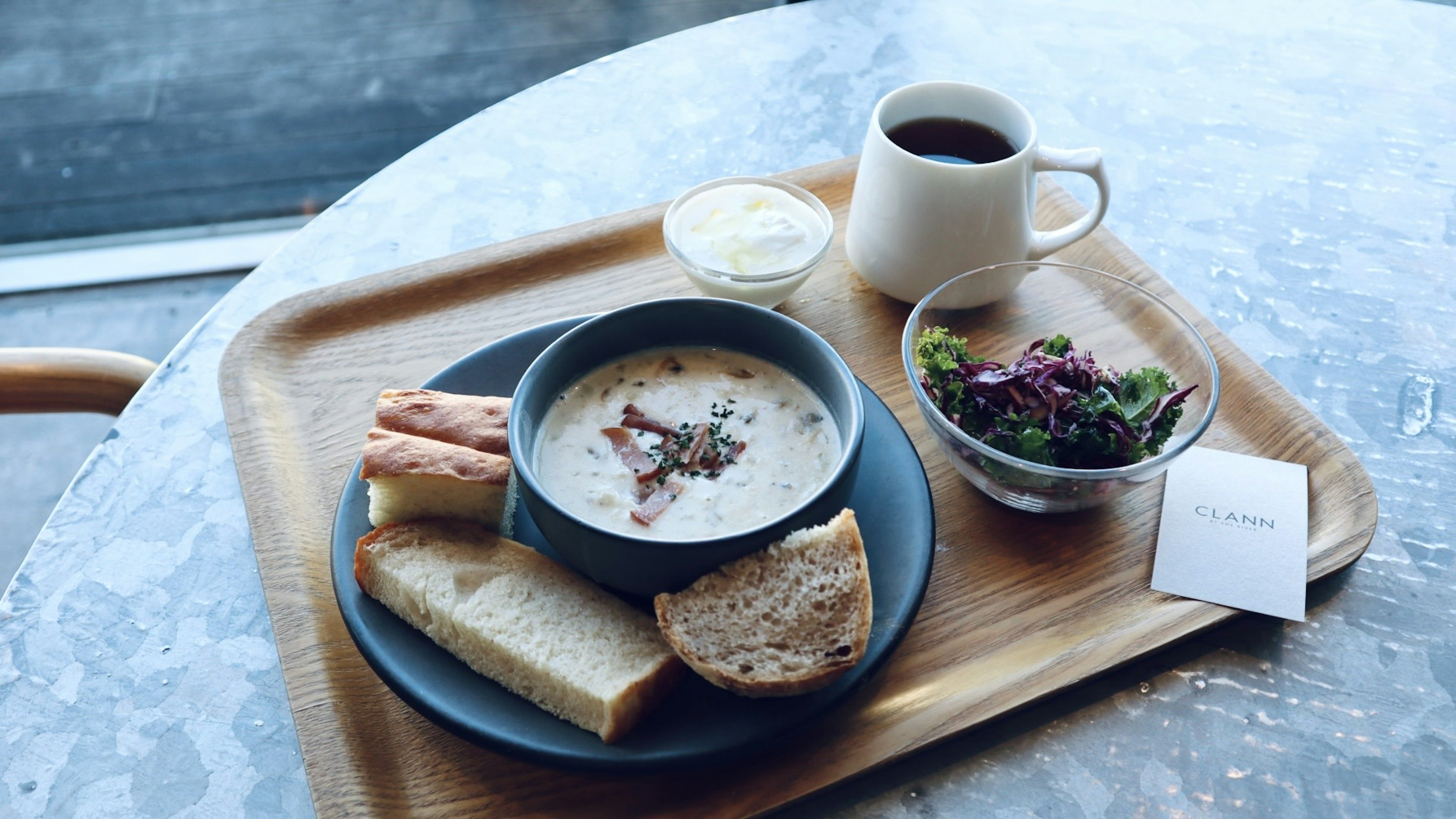 Bữa ăn gồm súp, salad, bánh mì và cà phê trên bàn