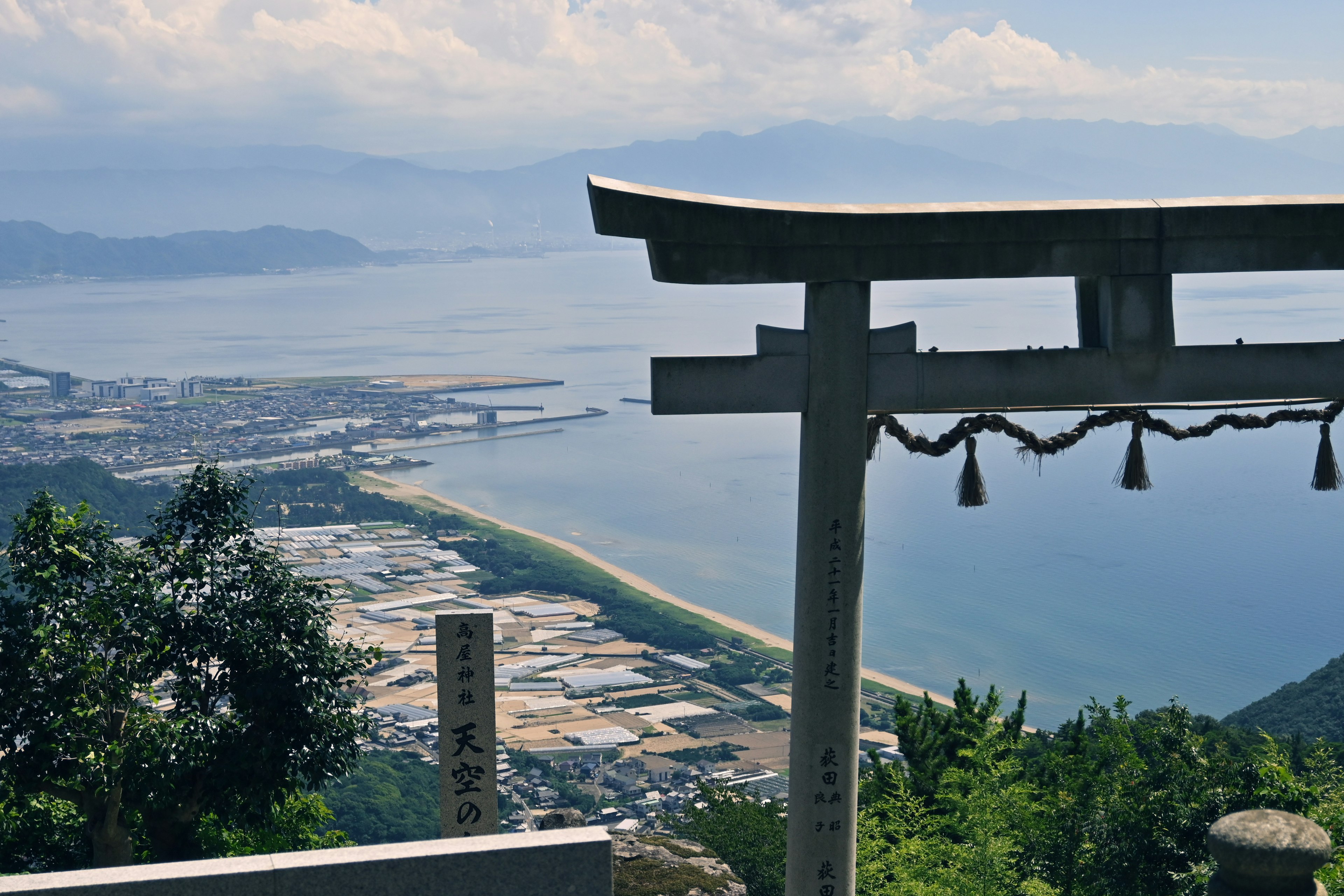 從山上俯瞰海洋和城鎮的美景 前景中有一個鳥居