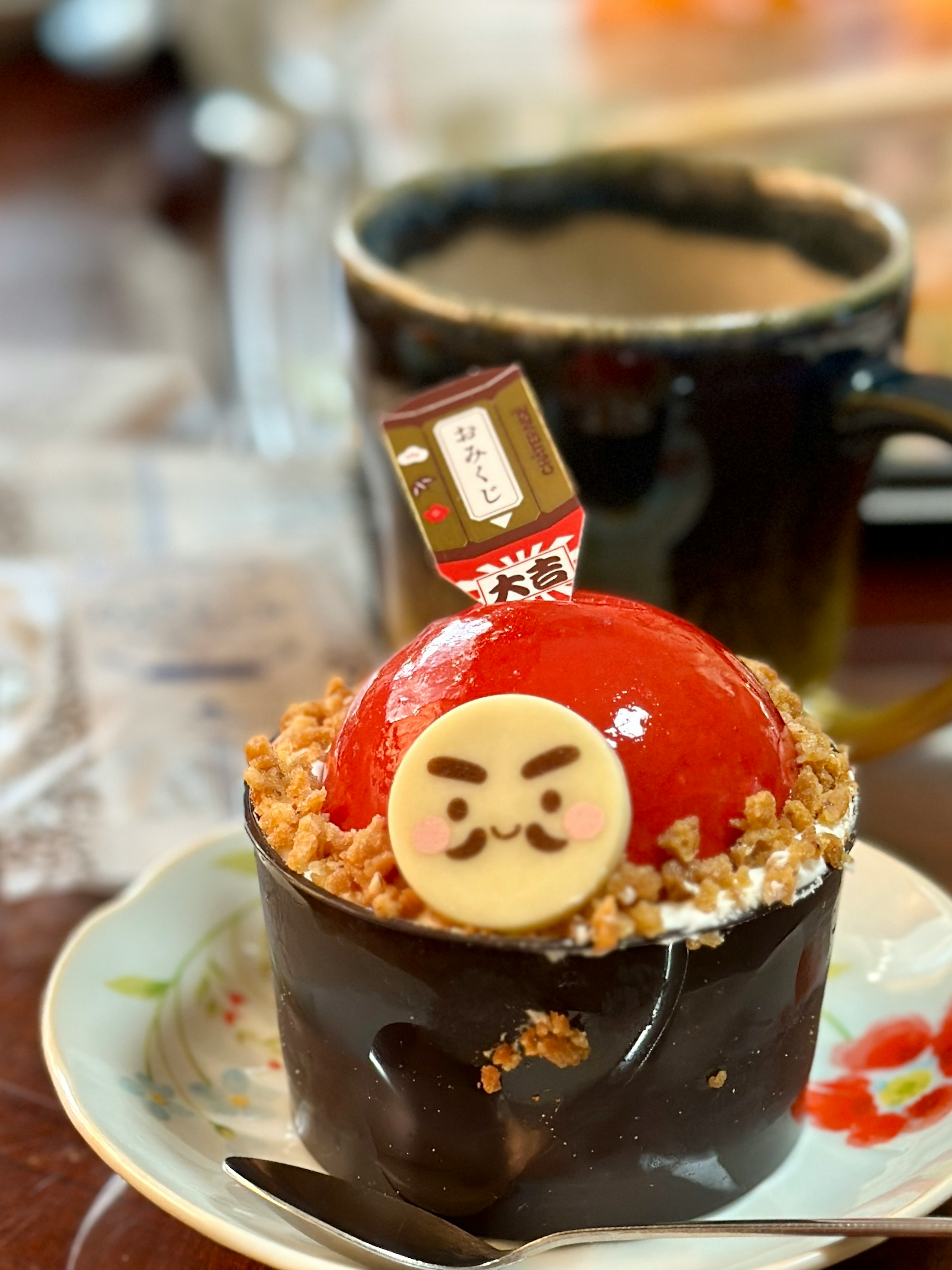 Dessert with a red dome topped by a character chocolate and surrounded by crumbs