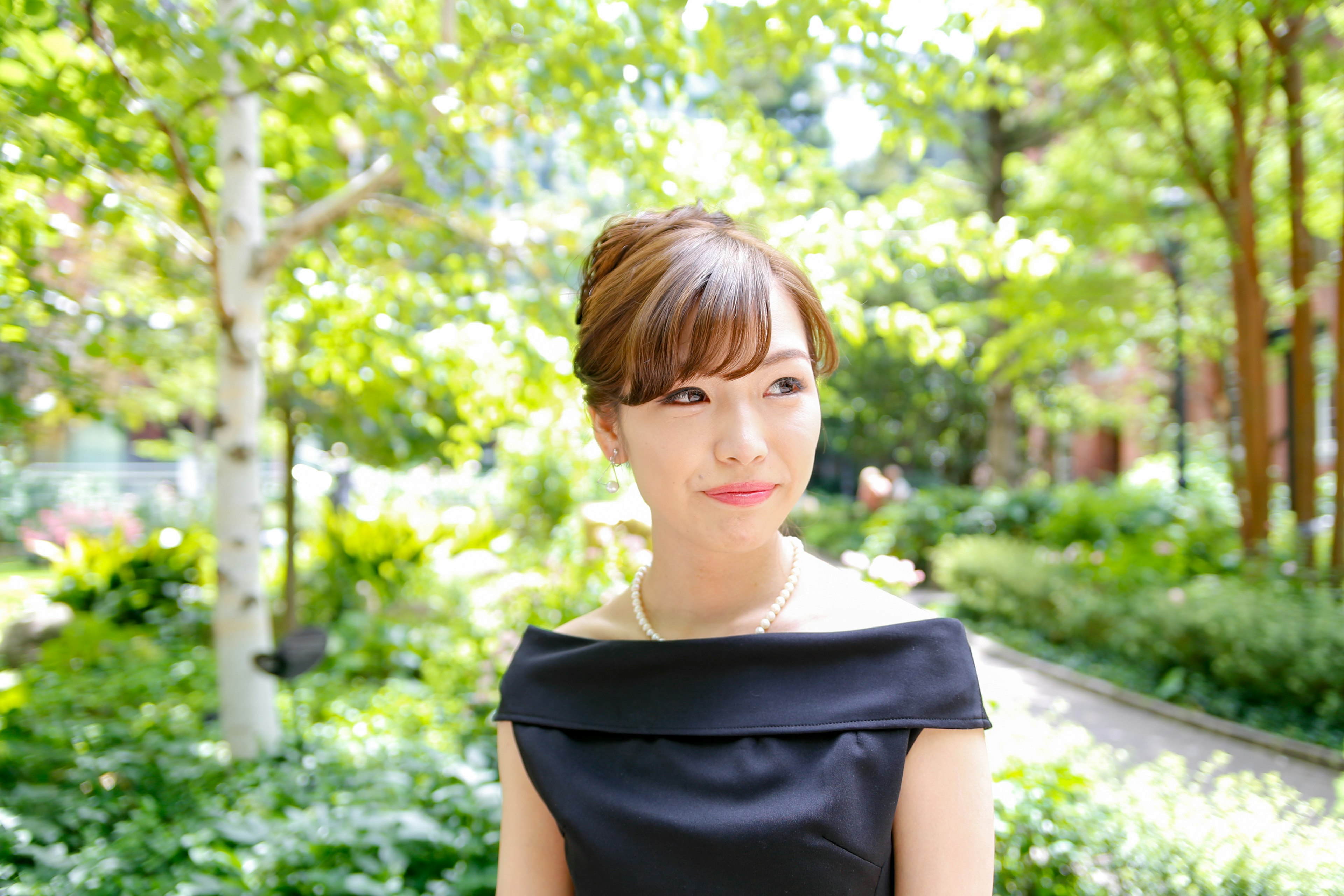 Femme souriante dans un jardin verdoyant portant une robe noire