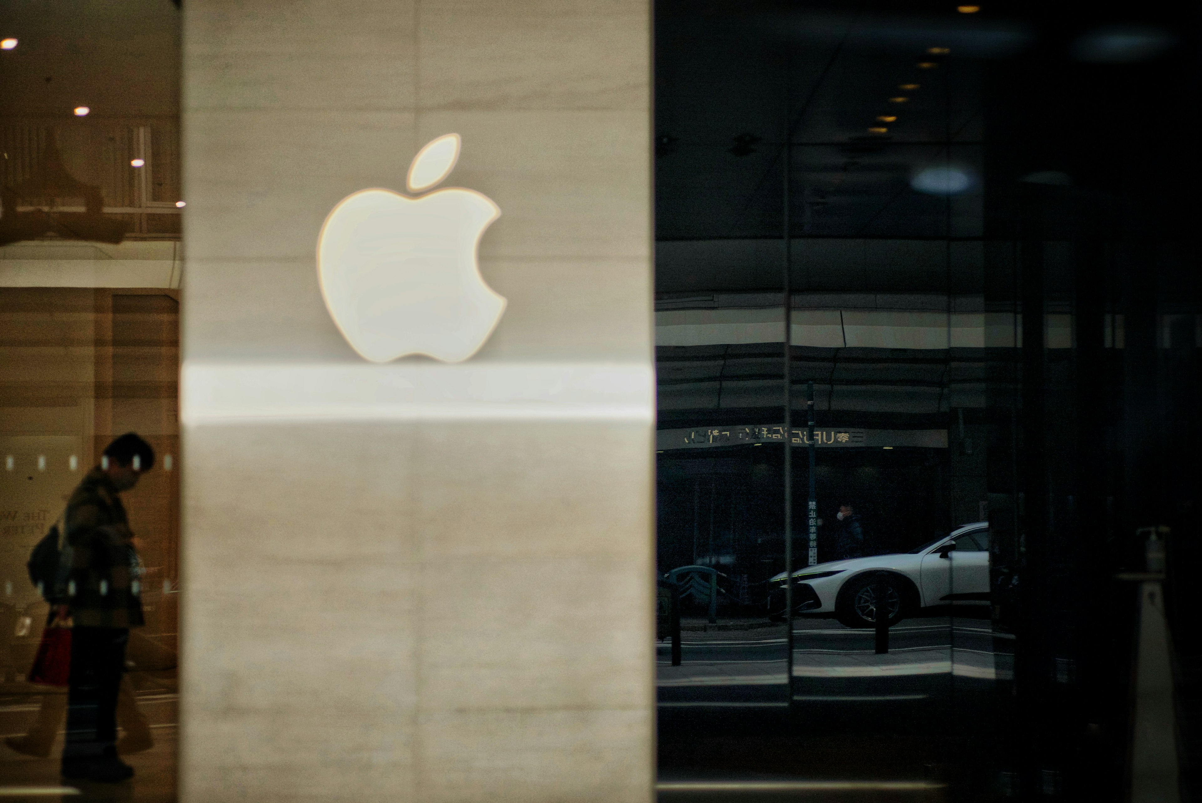 Logo Apple sur un mur en verre avec reflet de la rue