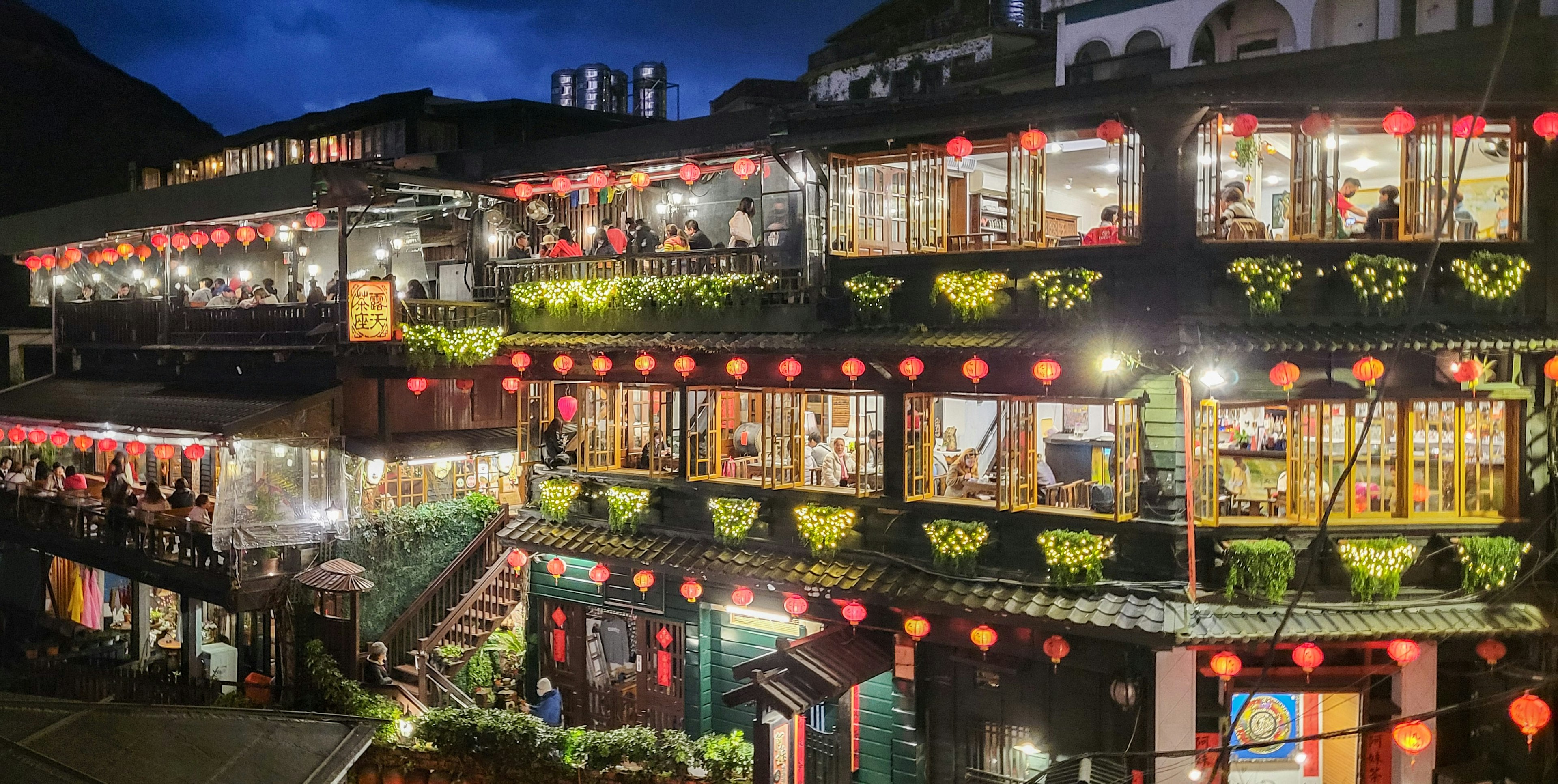 Restaurante y café de varios niveles adornados con faroles iluminando la noche