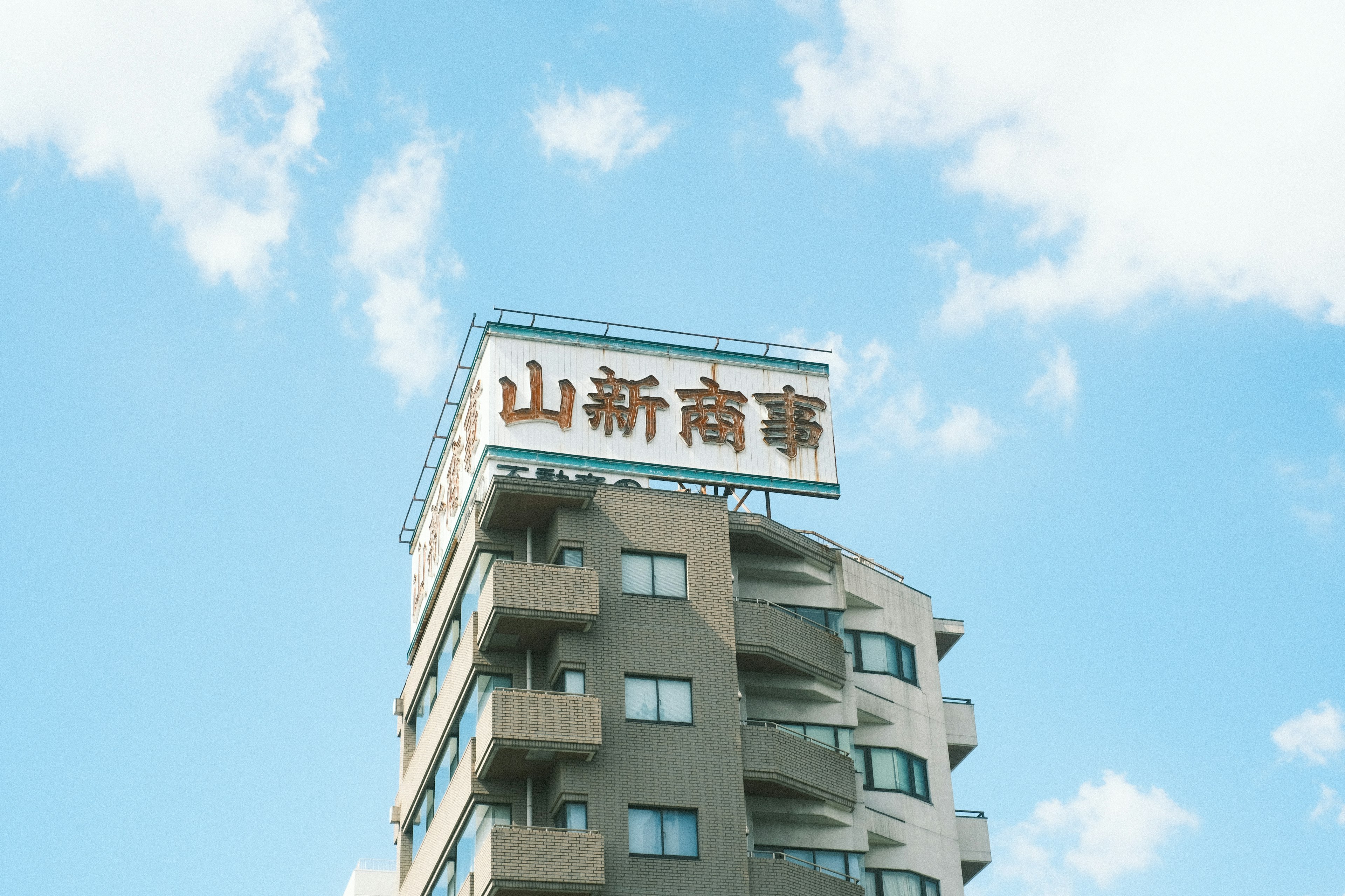 Ein hohes Gebäude mit einem Schild für Yama Shin Shoji unter einem blauen Himmel