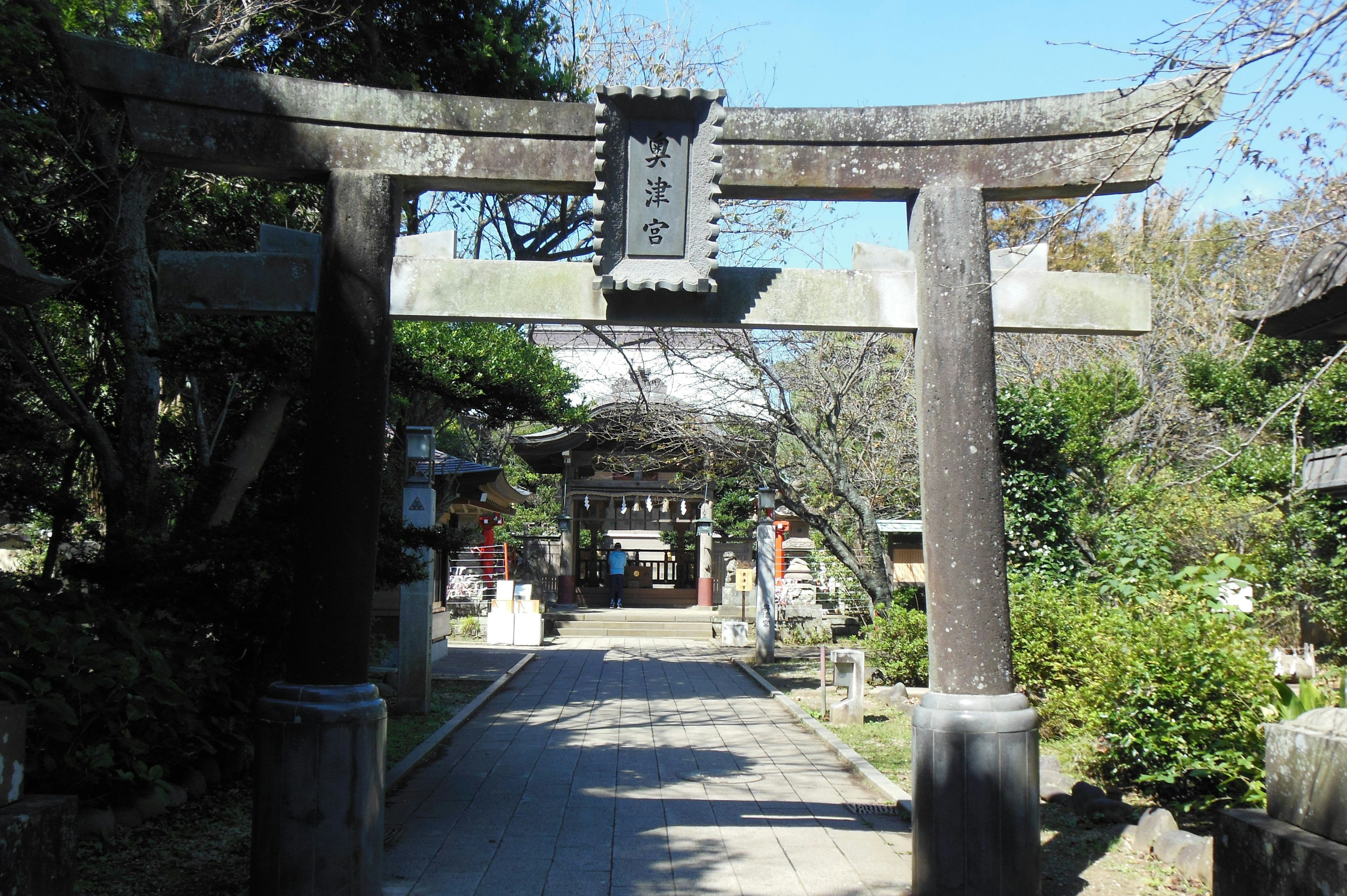 Entrance to a serene shrine with an ancient torii gate lush greenery and a stone pathway