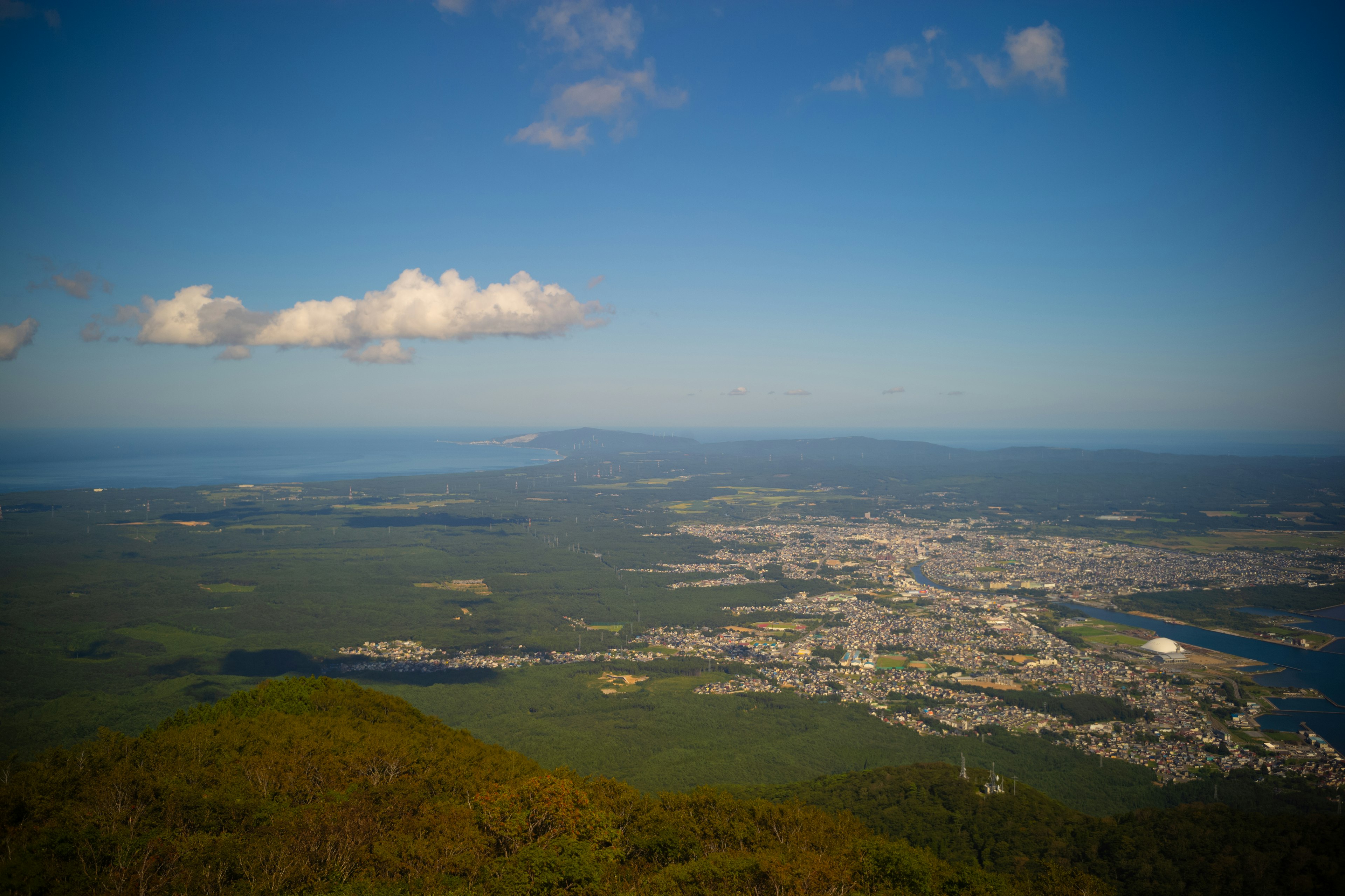 A scenic view from a mountain showing a city and the sea