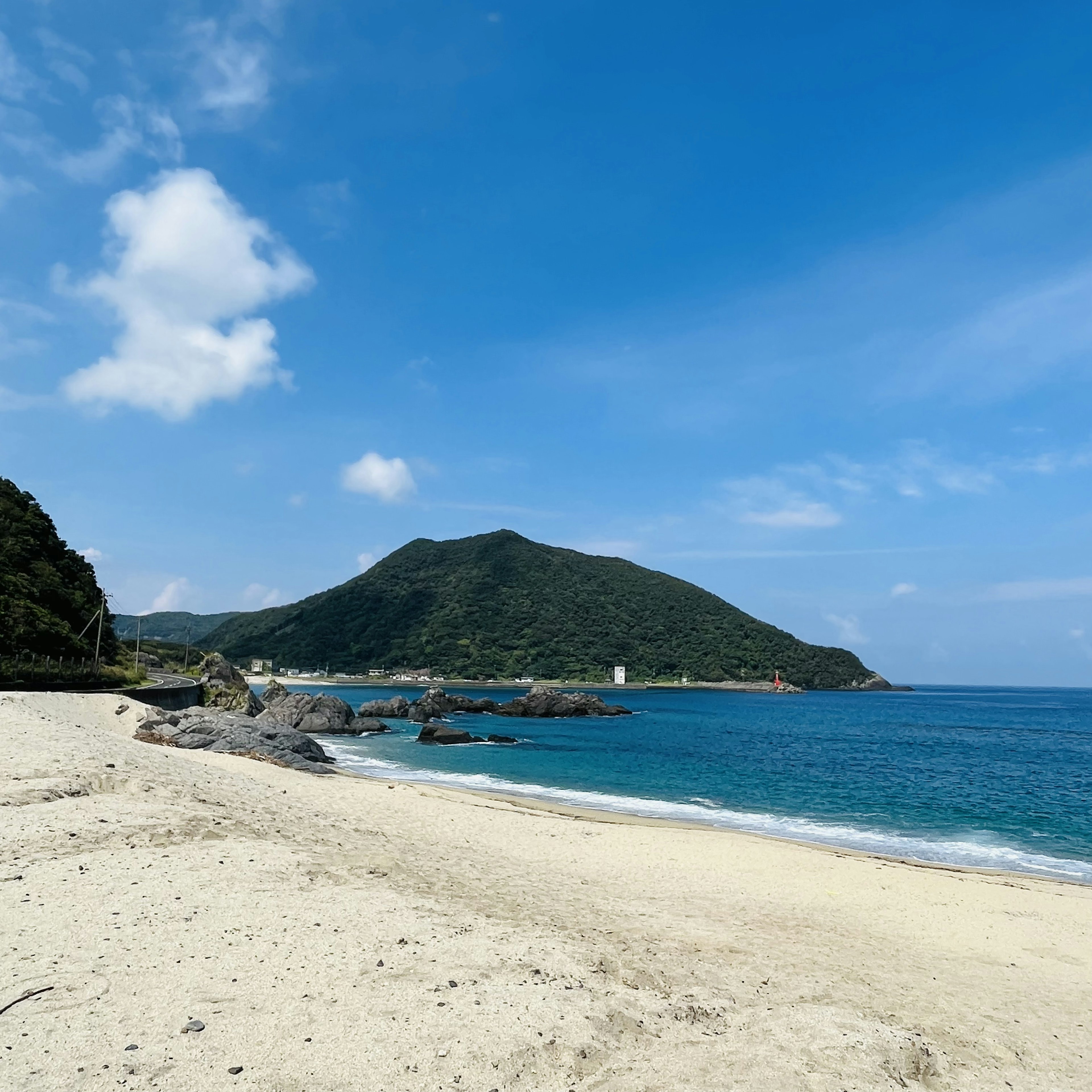 青い海と白い砂浜の風景 緑の山が背景に広がる