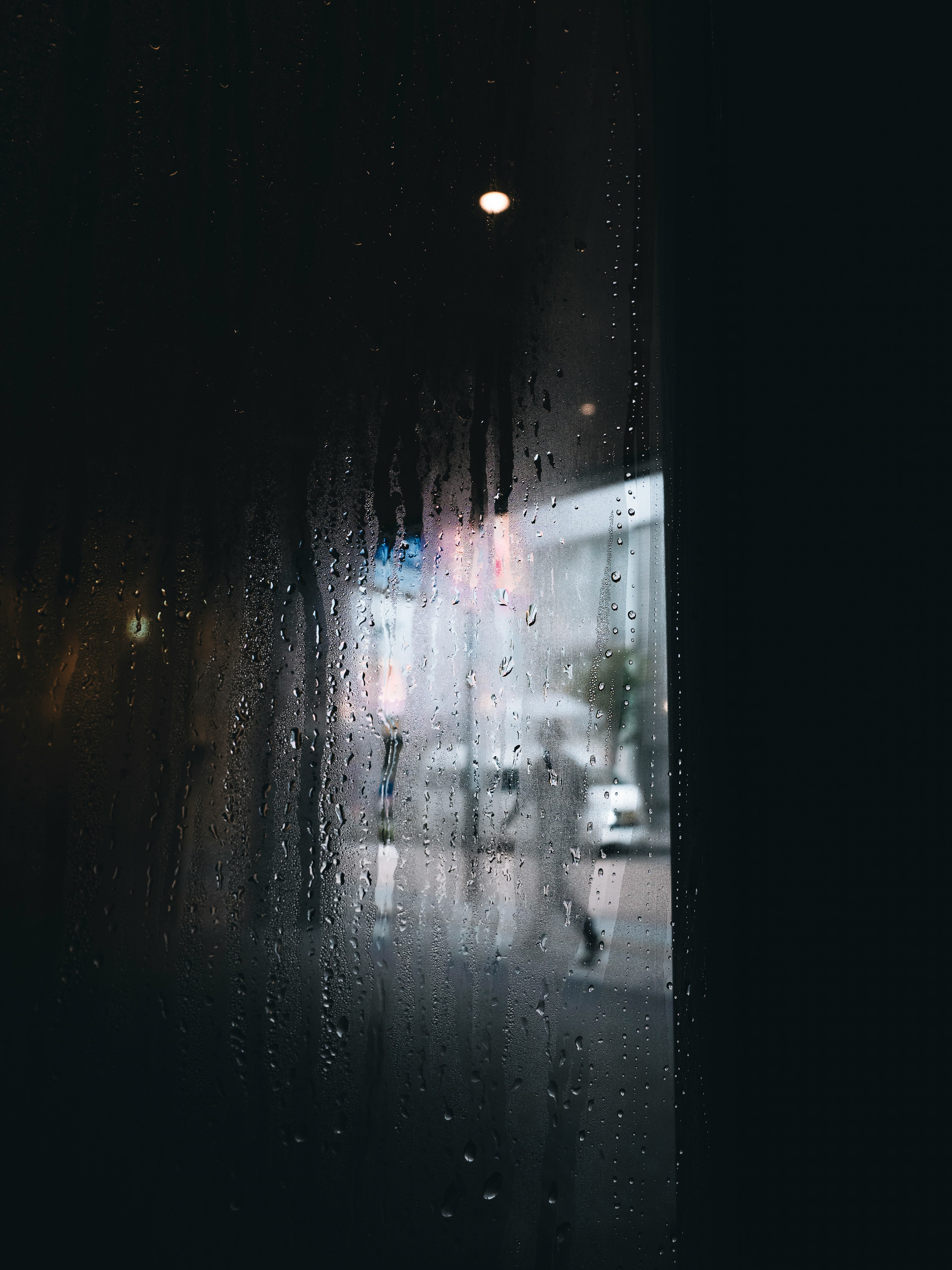 Vista de la ciudad y silueta de una persona a través de una ventana empañada