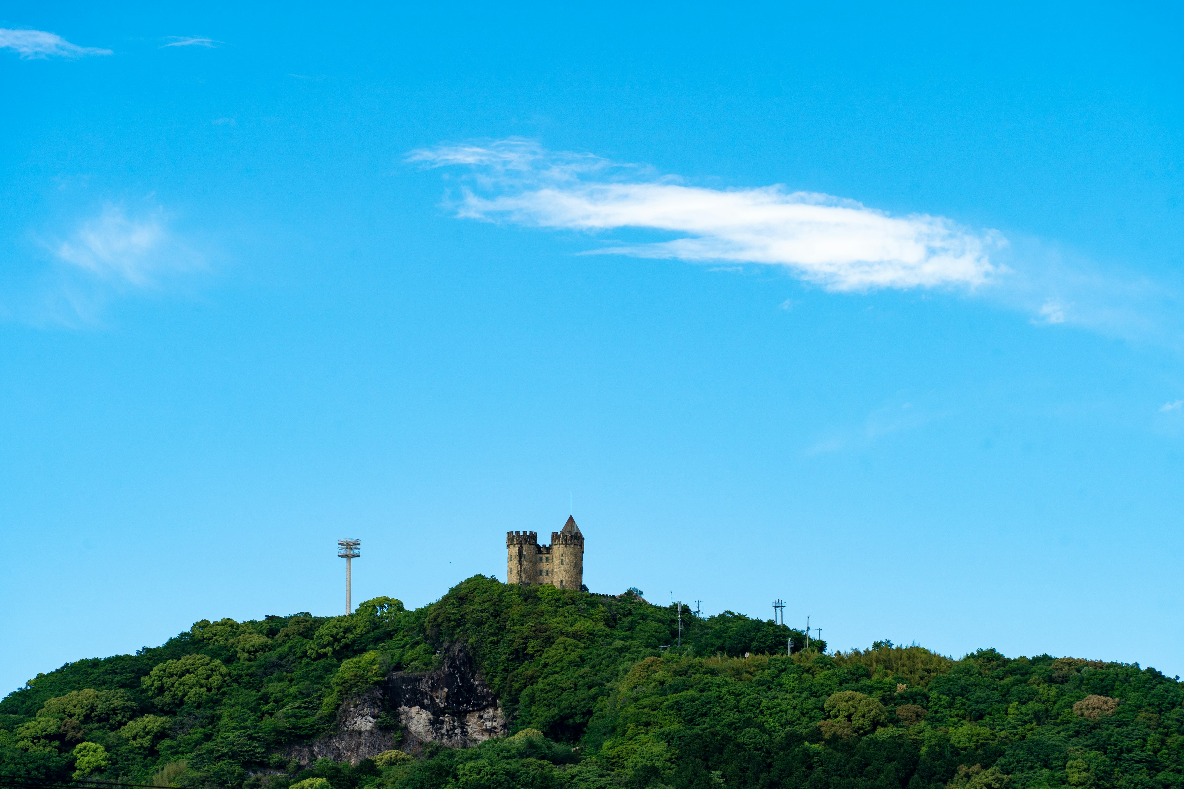 Un vieux château situé sur une colline verte sous un ciel bleu