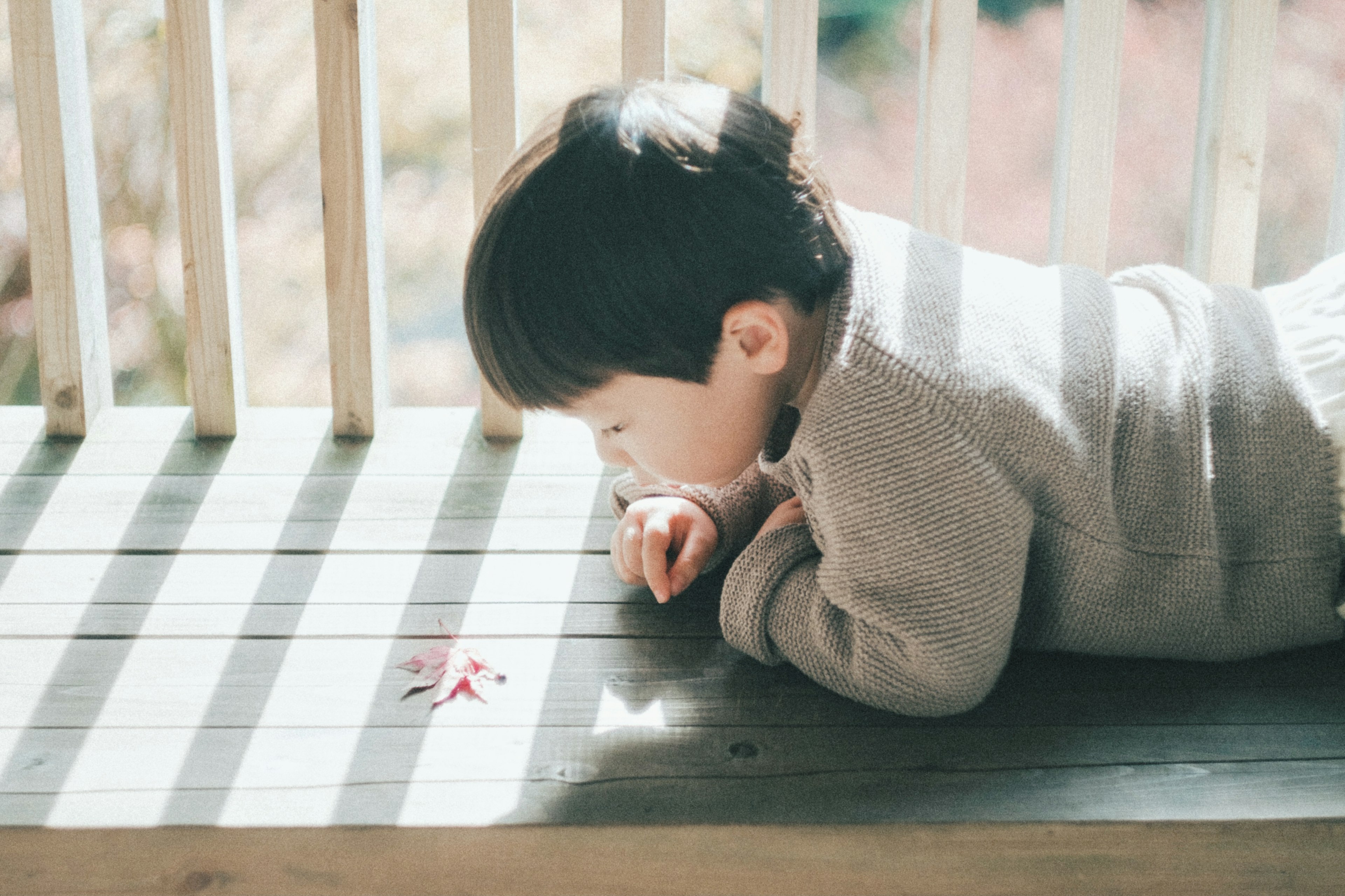 Enfant allongé sur le sol en bois regardant de petits objets